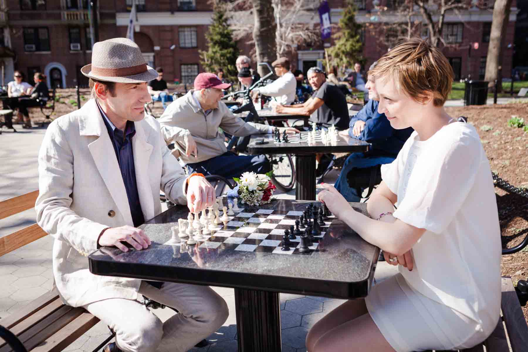 Man and woman playing chess in park for an article entitled, ‘Are Couples Still Getting Married?’