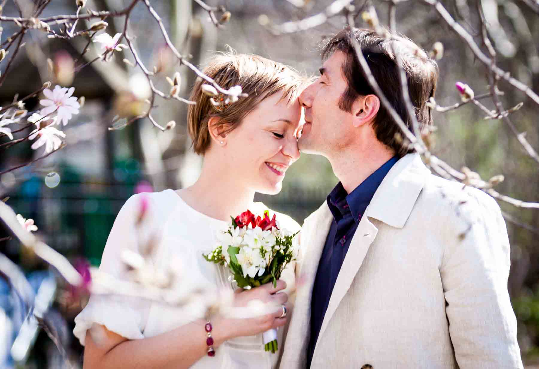 Man kissing woman with short hair on the forehead for an article entitled, ‘Are Couples Still Getting Married?’