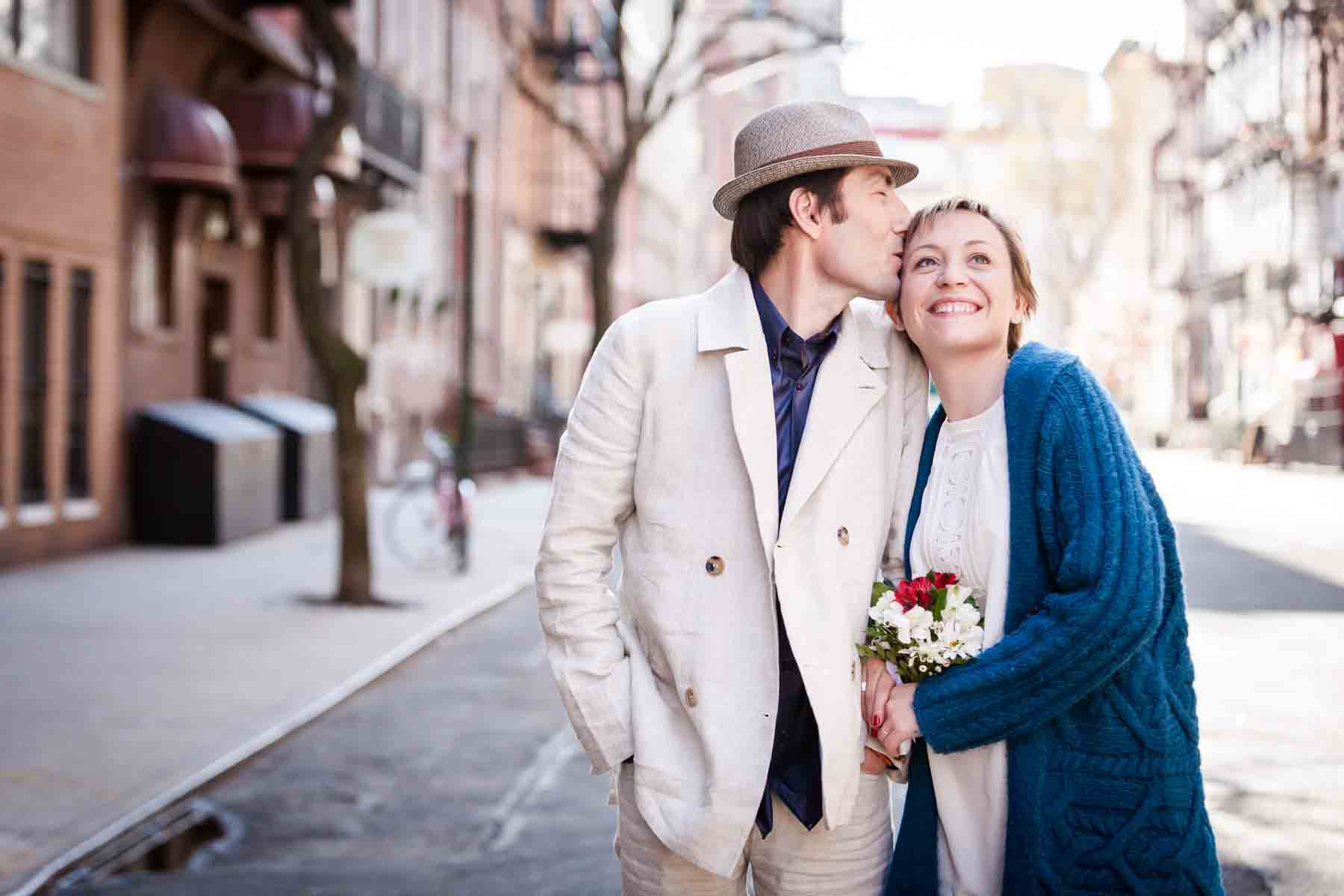 Man kissing woman on side of head while walking down street for an article entitled, ‘Are Couples Still Getting Married?’