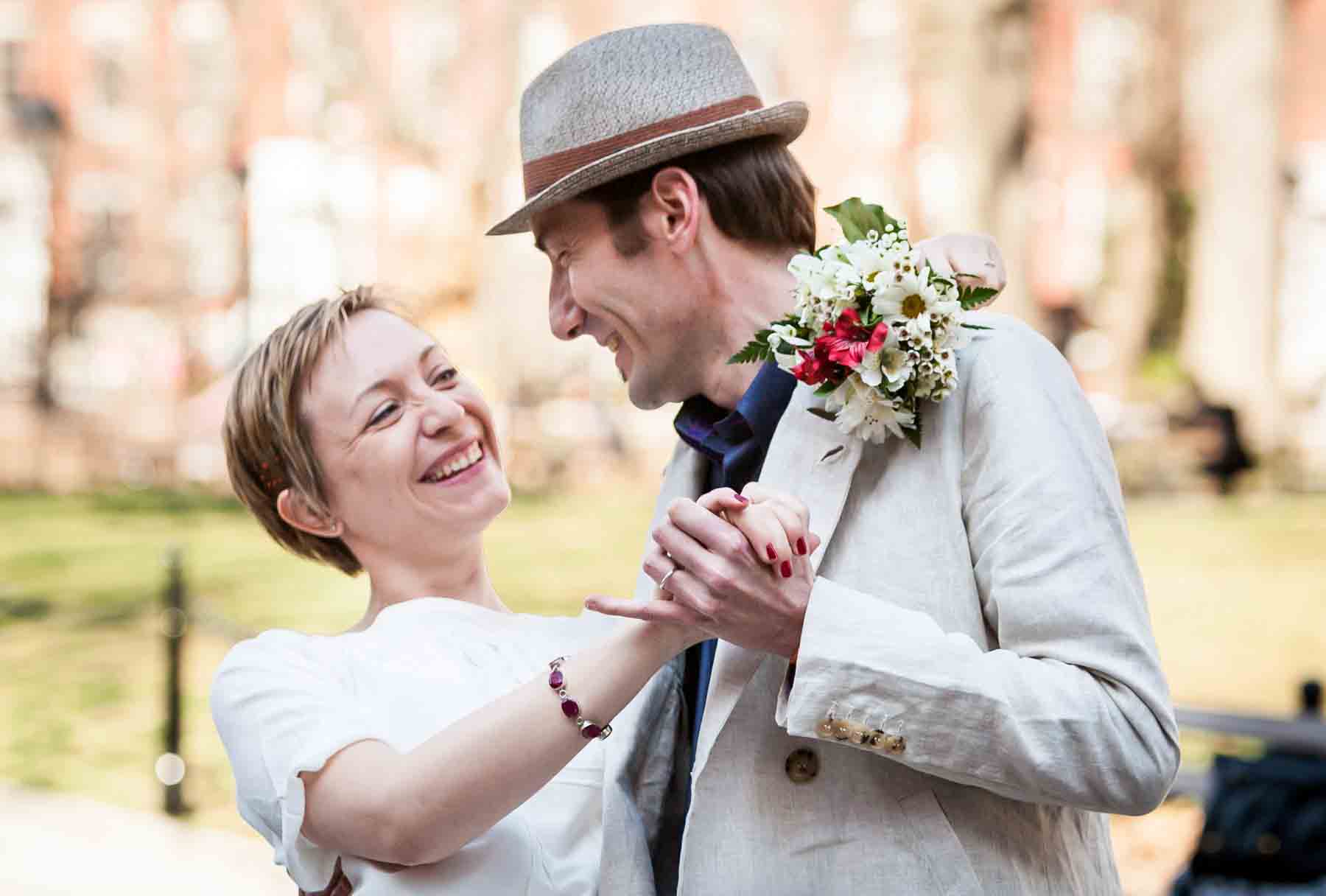 Woman with short hair dancing with man while holding flowers for an article entitled, ‘Are Couples Still Getting Married?’