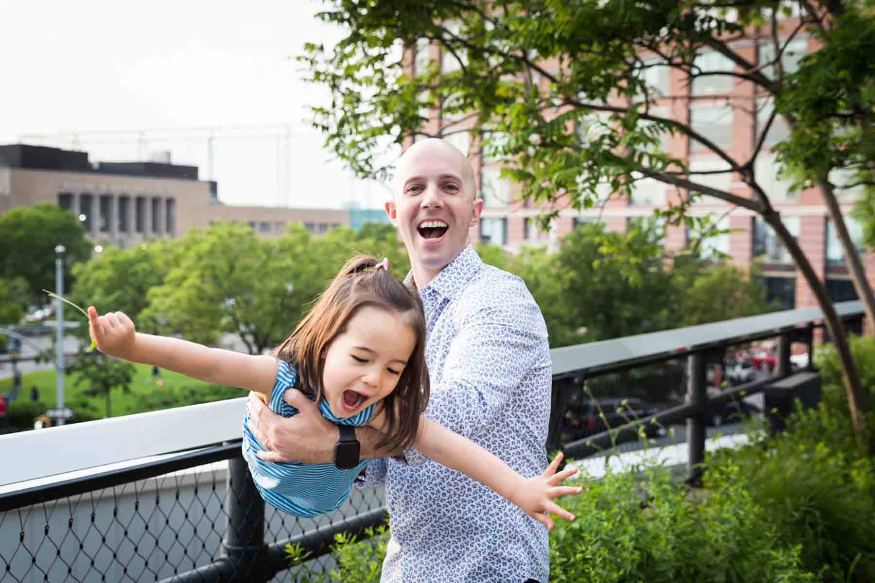 Father playing airplane with little girl with arms outstretched for an article on daddy and me photo shoot ideas