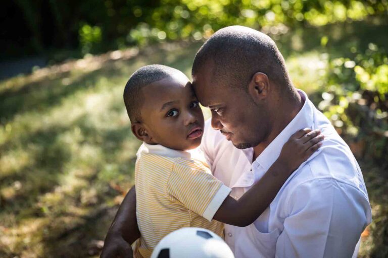 African American father and son touching foreheads in a park for an article on daddy and me photo shoot ideas