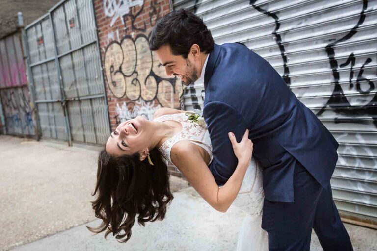 Bride and groom dancing on sidewalk in front of graffiti for an article on how to save money on wedding photography