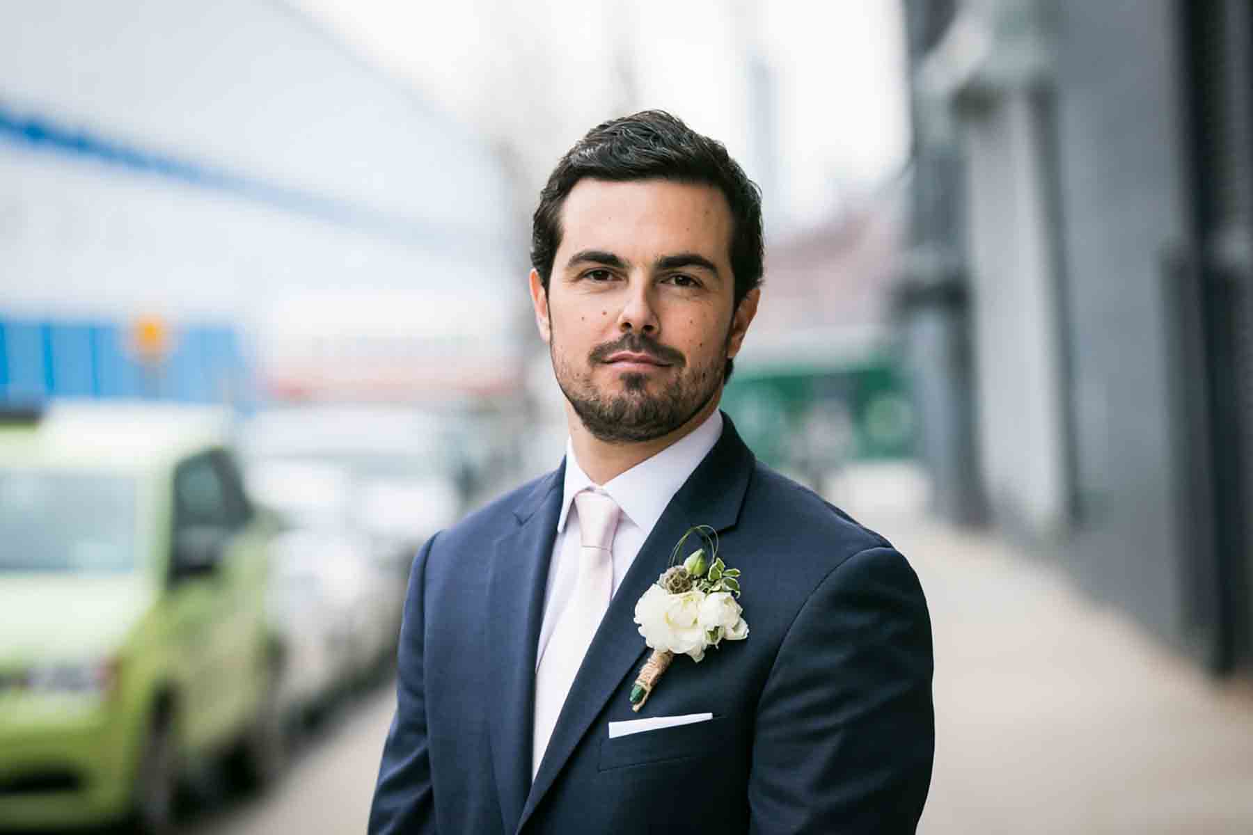 Groom wearing grey blazer and beard on sidewalk for an article on how to save money on wedding photography