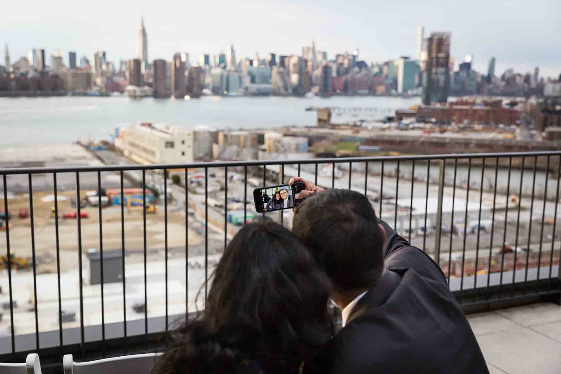 Couple taking selfie with NYC skyline in the background for an article on how to save money on wedding photography