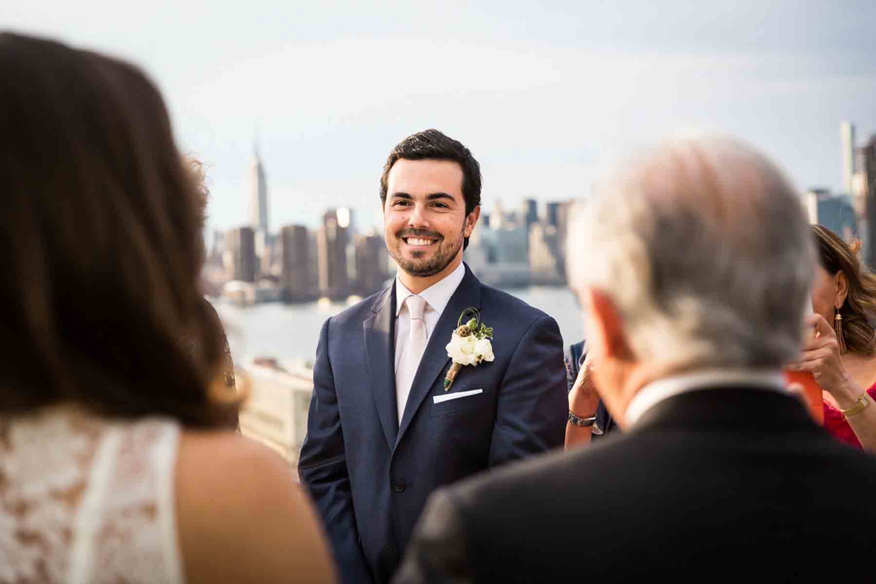 Groom watching bride and father walk down aisle for an article on how to save money on wedding photography
