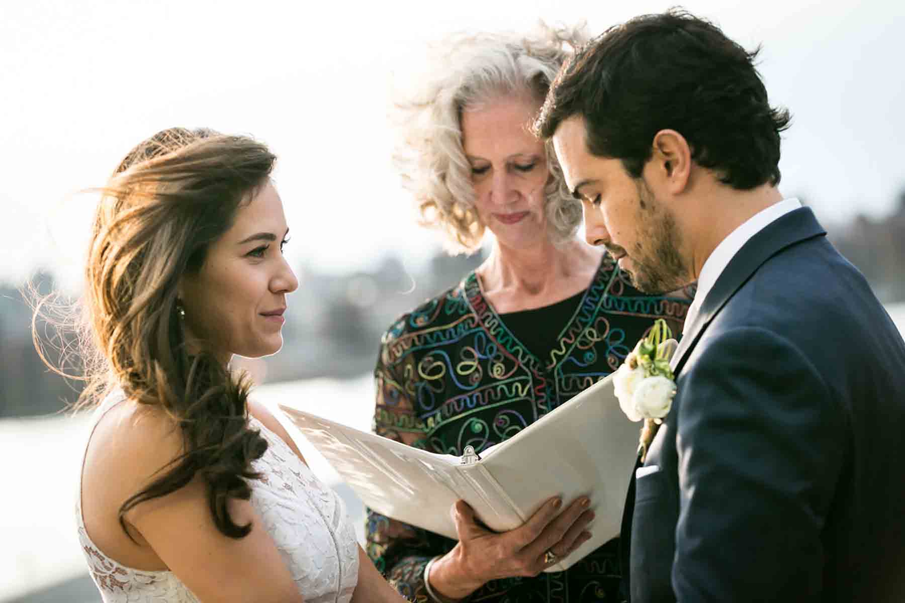 Bride and groom standing in front of officiant during ceremony for an article on how to save money on wedding photography