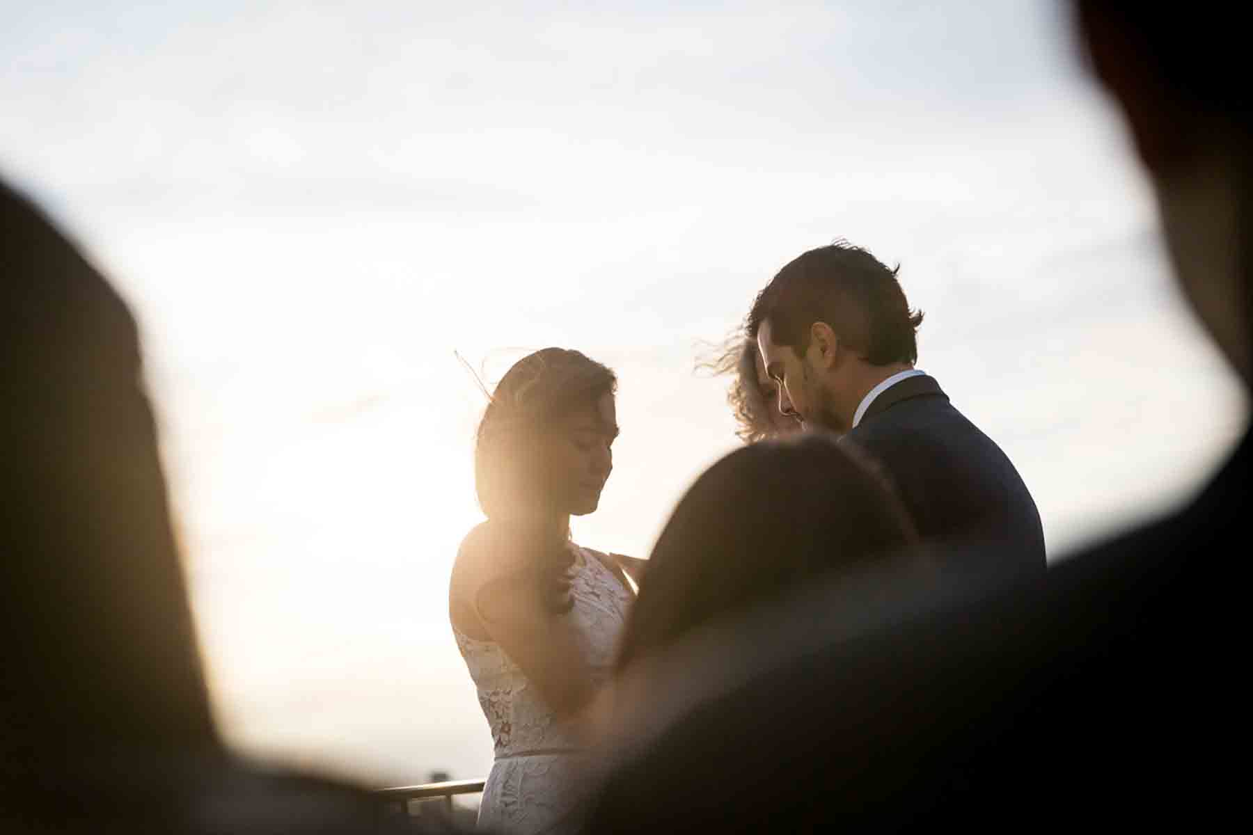 Bride and groom saying vows with sun flare for an article on how to save money on wedding photography