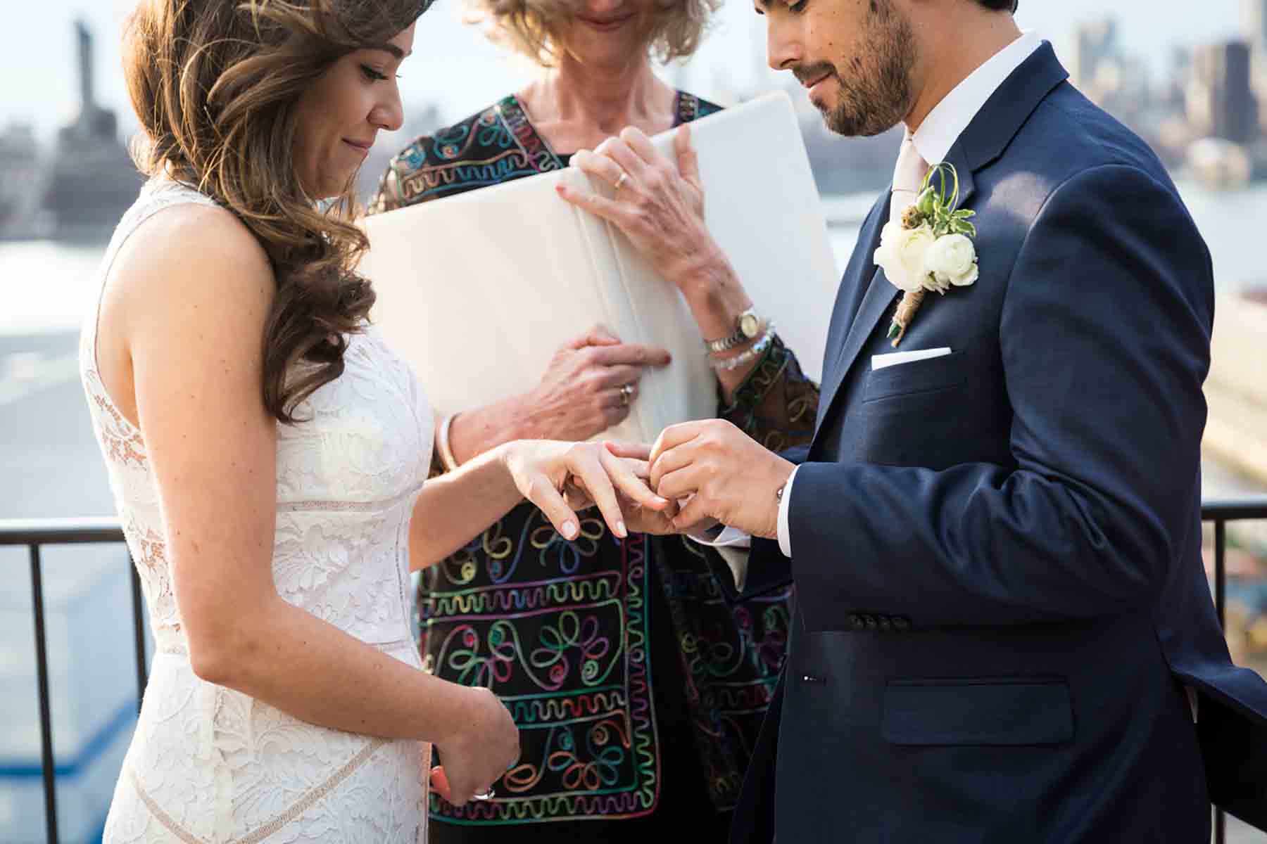 Groom putting ring on bride's finger for an article on how to save money on wedding photography