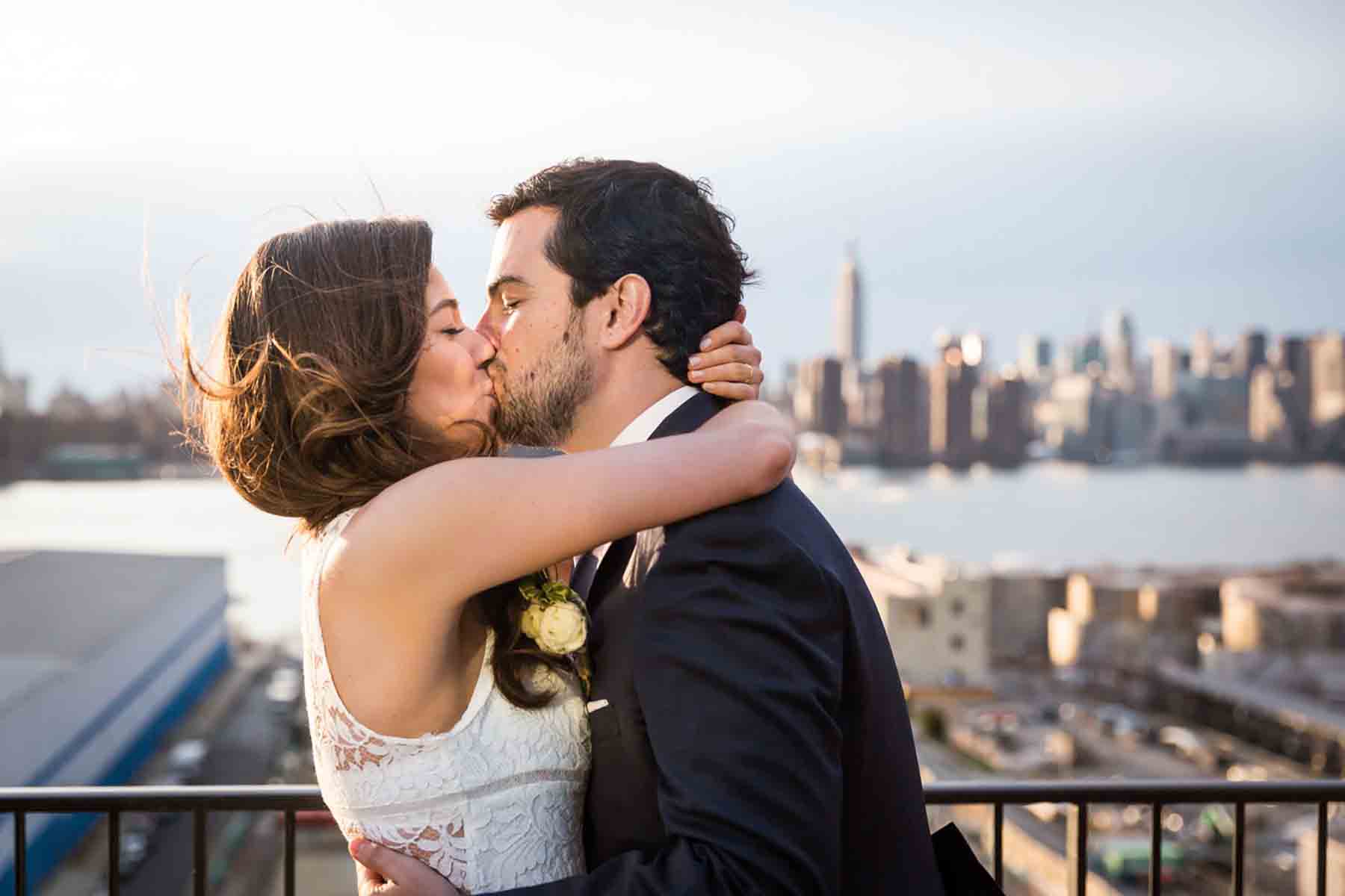 Bride and groom kissing with NYC skyline in background for an article on how to save money on wedding photography