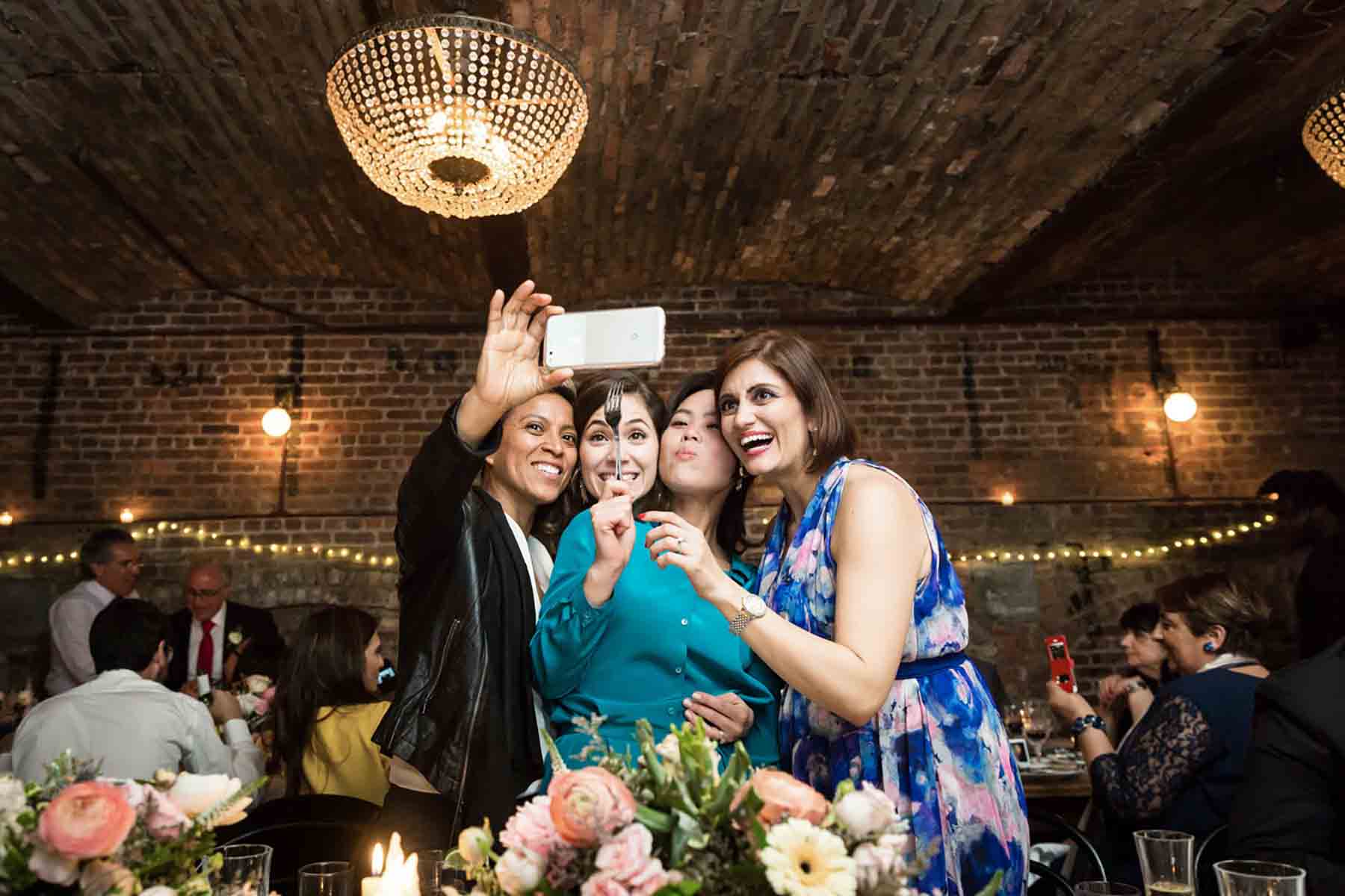 Four female guests taking selfie at reception for an article on how to save money on wedding photography