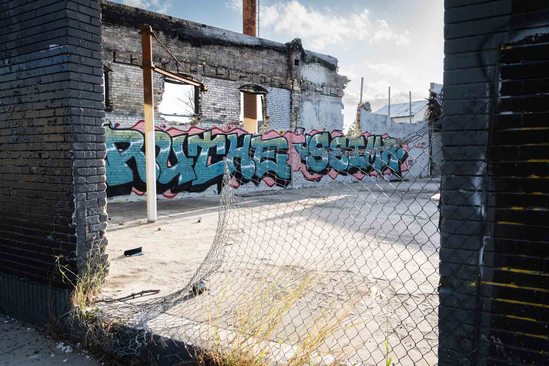 Abandoned building site with colorful graffiti and bent wire fence for an article on secret San Antonio photo shoot locations