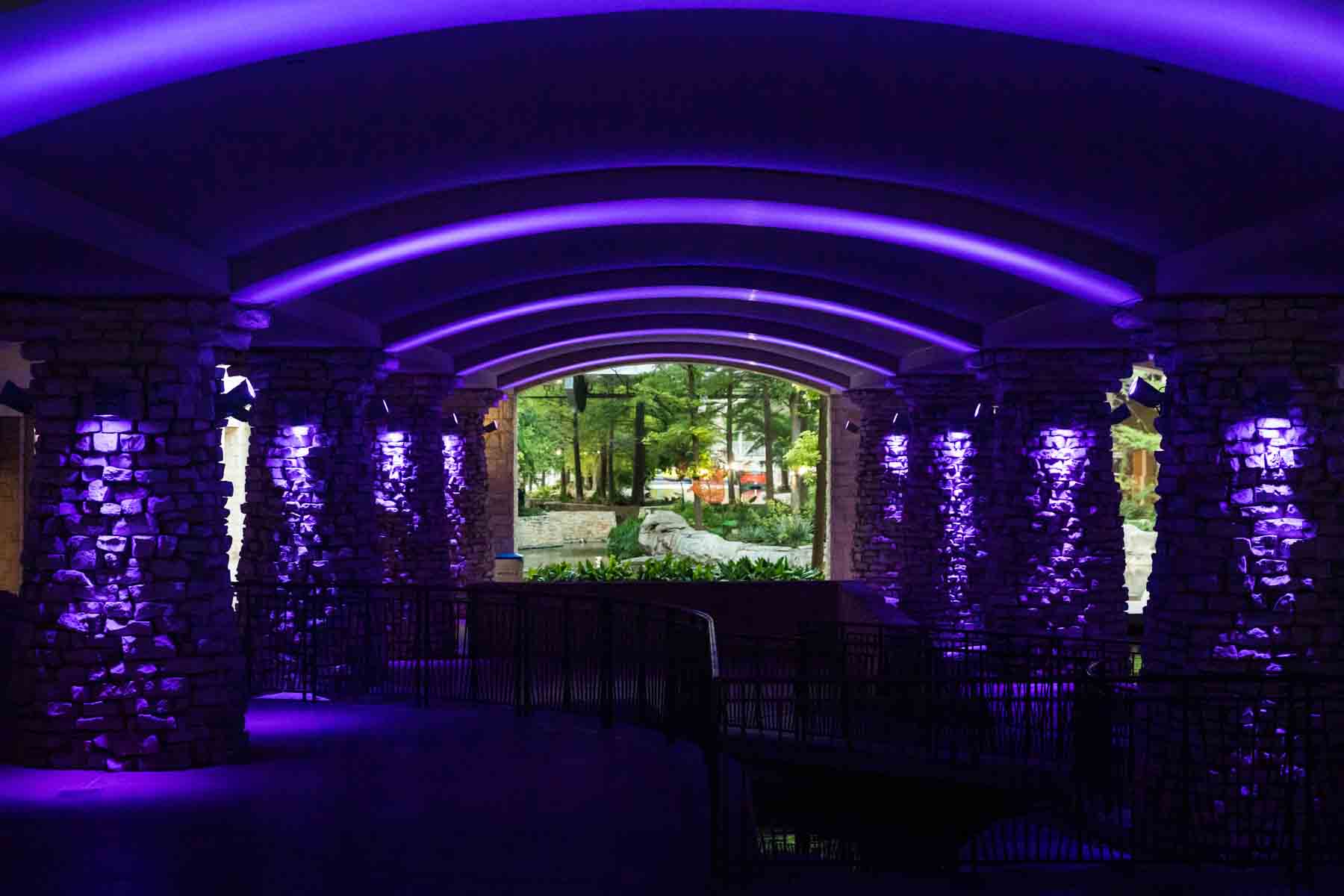 Underground space lit with purple lights against brick columns for an article on secret San Antonio photo shoot locations