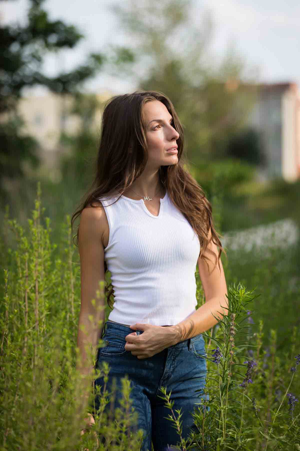 Model in white, sleeveless shirt standing in green bushes for an article announcing a downtown San Antonio photo shoot neighborhood discount