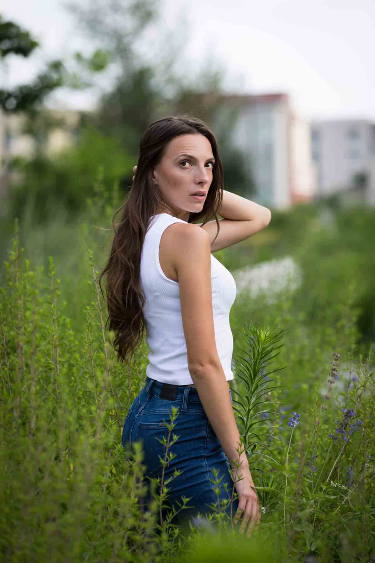 Model in white, sleeveless shirt standing in green bushes for an article announcing a downtown San Antonio photo shoot neighborhood discount