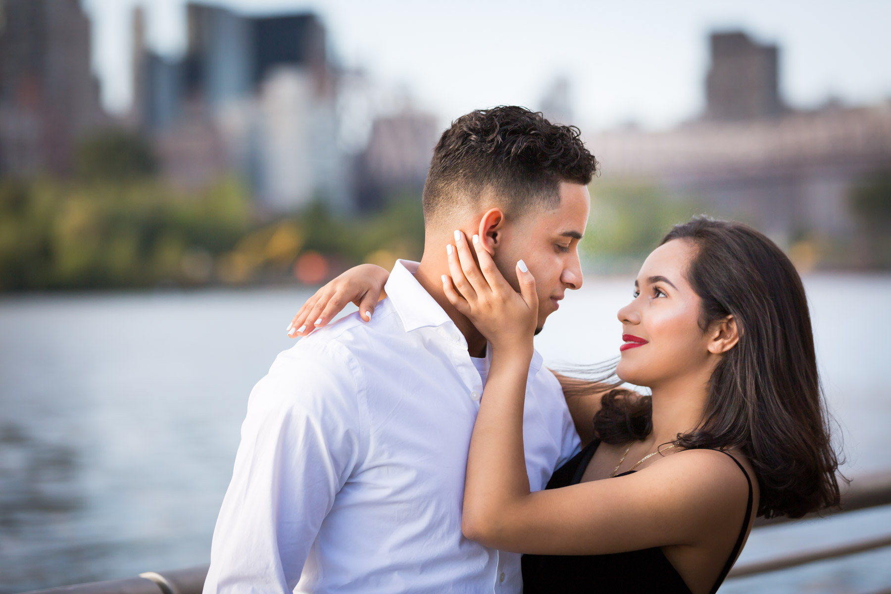 Couple about to kiss in front of railing with city skyline in background for an article on how to beat the summer heat during a photo shoot