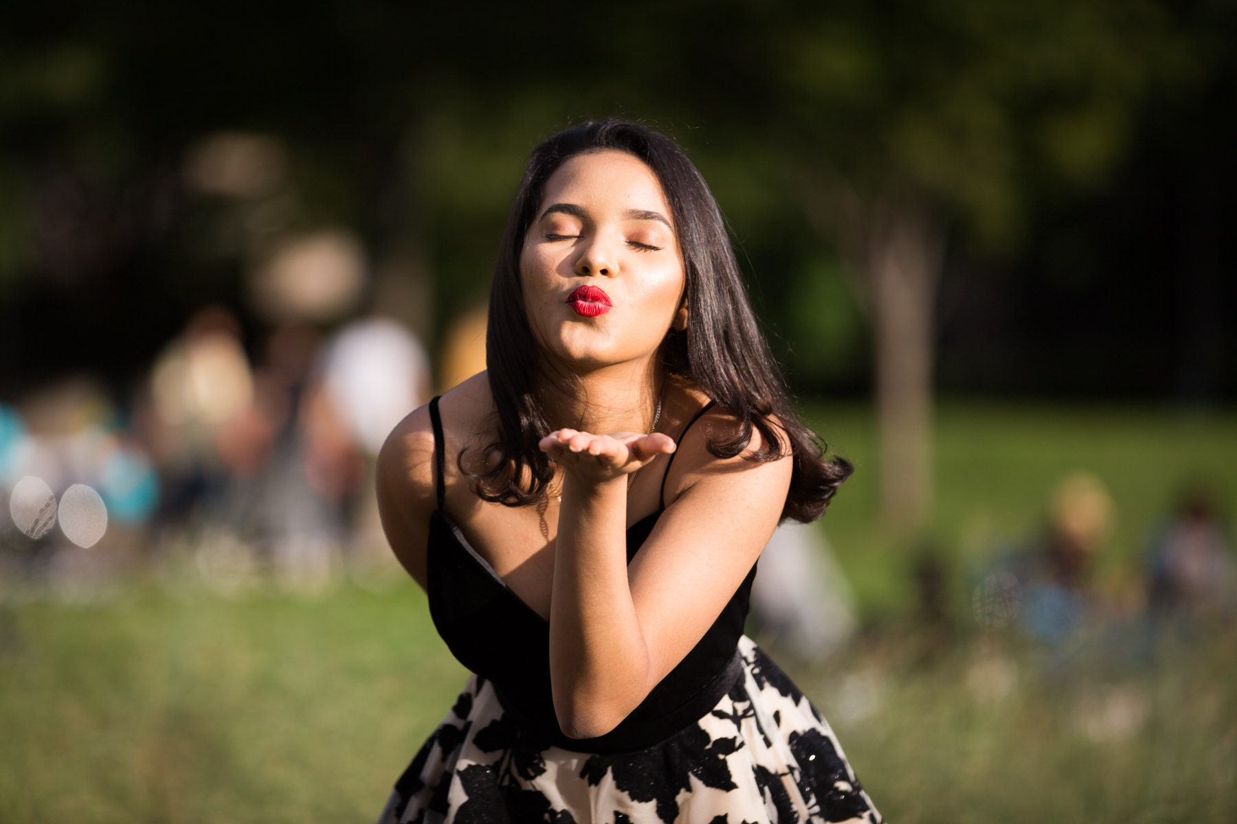 Smiling woman with brown hair and red lipstick blowing a kiss for an article on how to beat the summer heat during a photo shoot