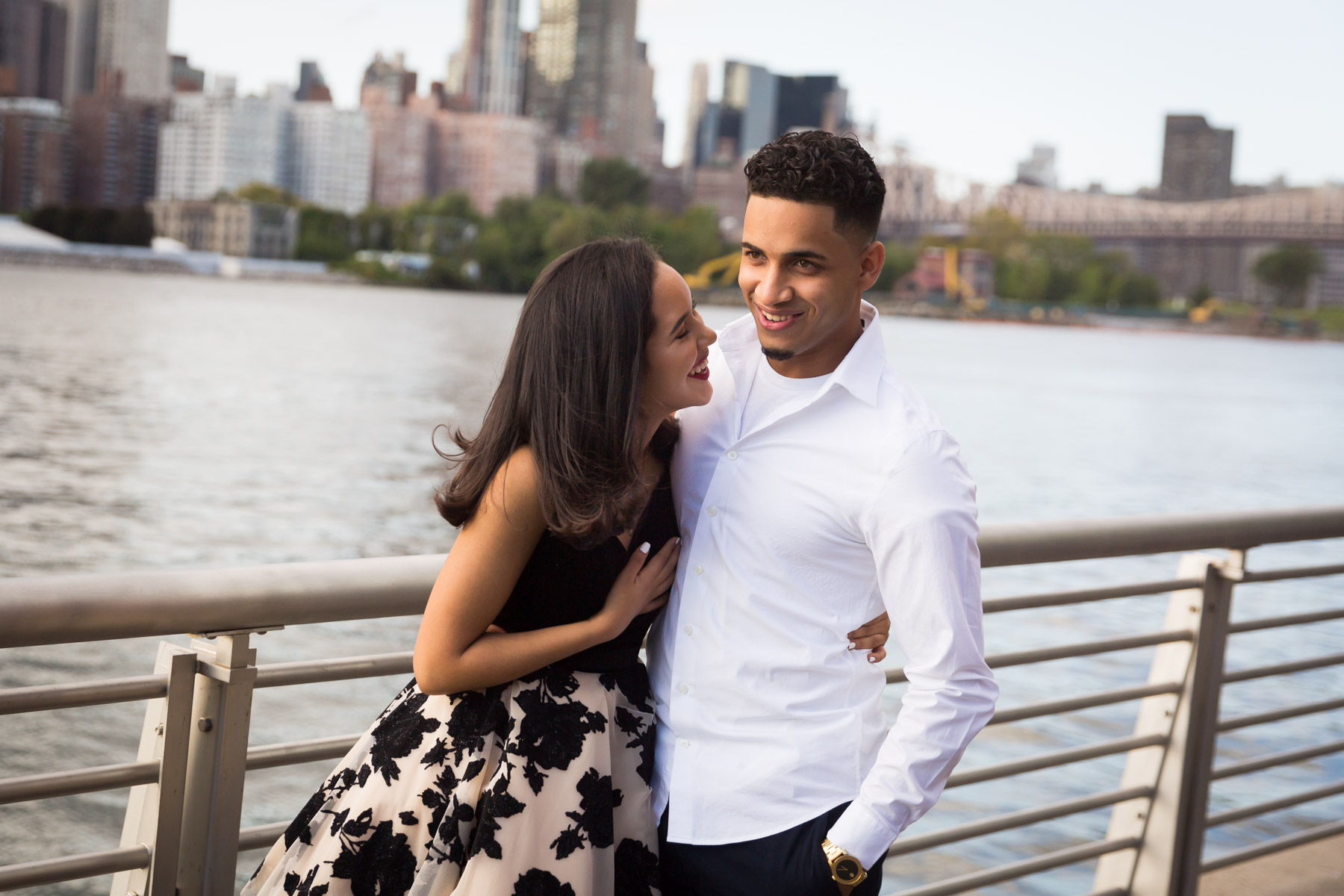 Couple hugging in front of railing with city skyline in background for an article on how to beat the summer heat during a photo shoot