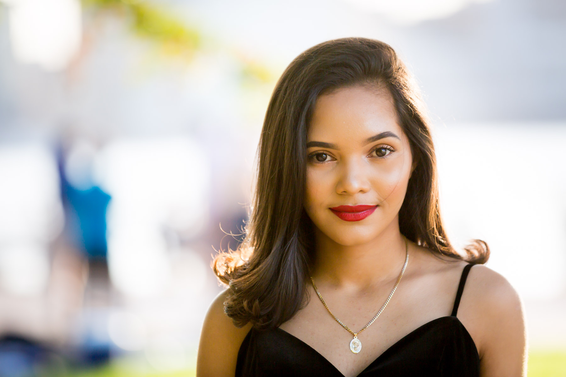 Smiling woman with brown hair and red lipstick at sunset for an article on how to beat the summer heat during a photo shoot