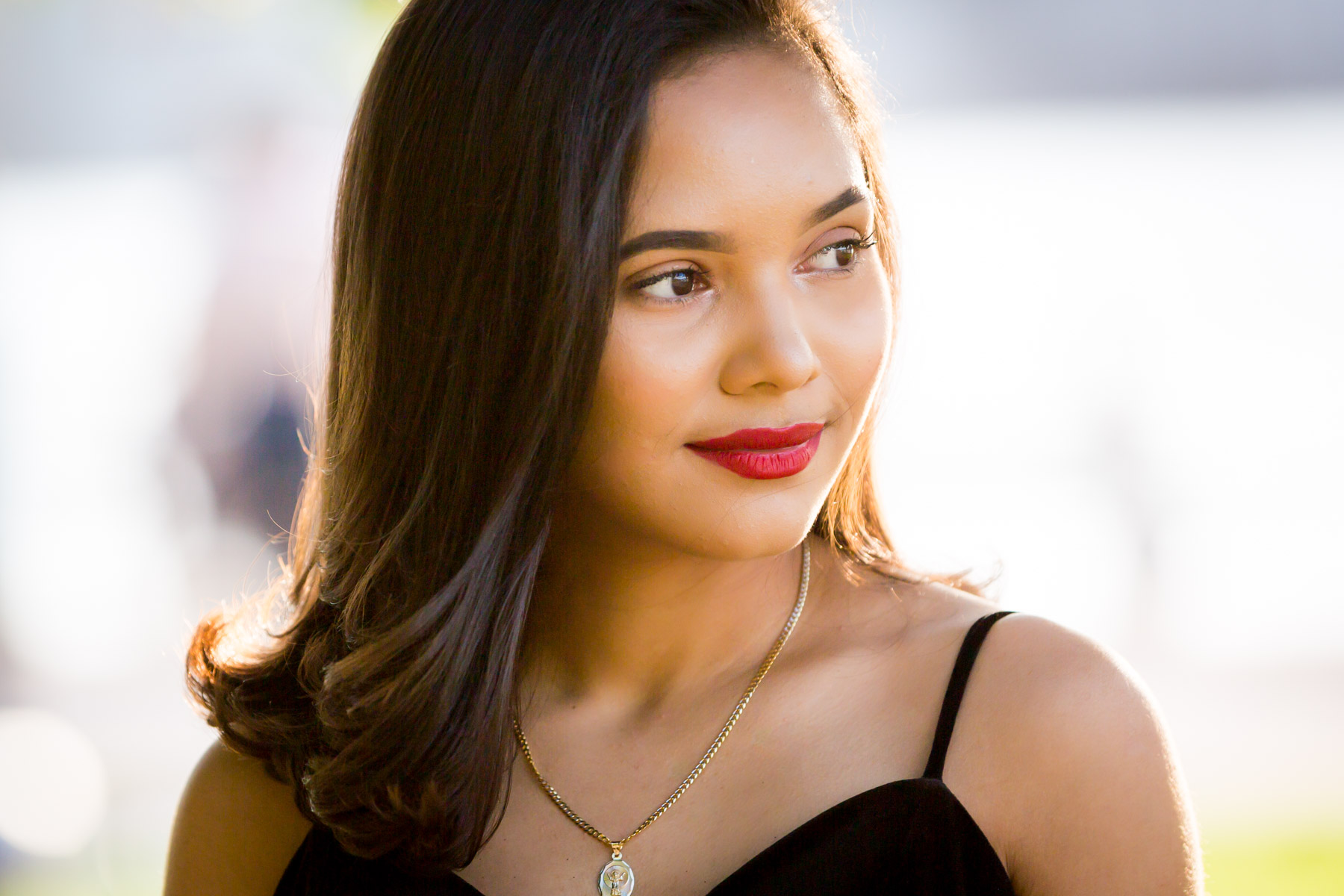 Smiling woman with brown hair and red lipstick at sunset for an article on how to beat the summer heat during a photo shoot