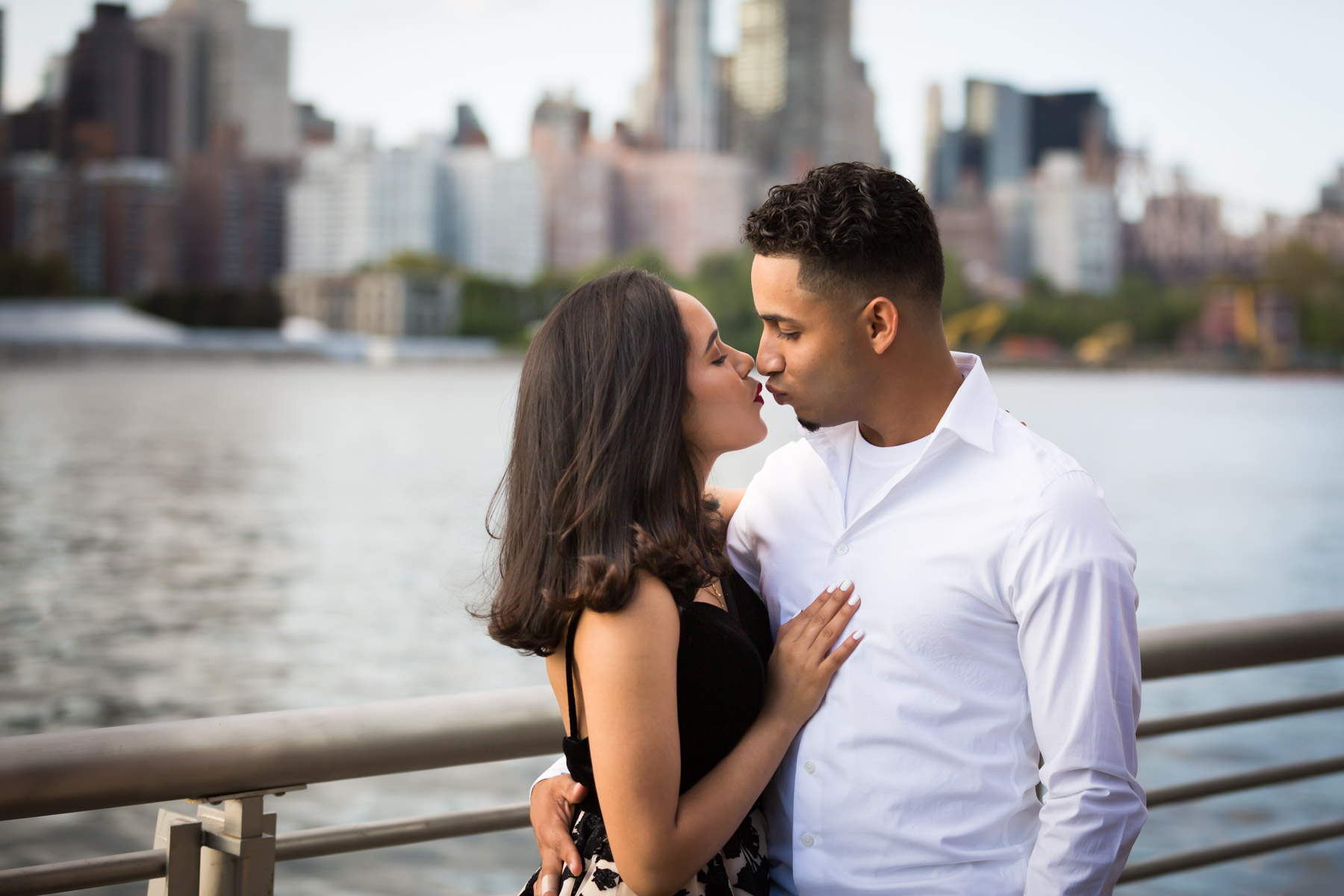 Couple hugging in front of railing with city skyline in background for an article on how to beat the summer heat during a photo shoot