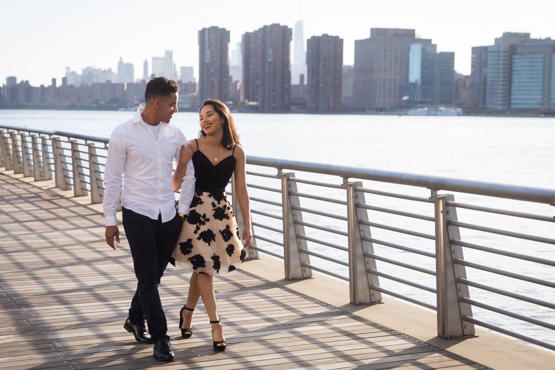 Couple walking on boardwalk with city skyline in background for an article on how to beat the summer heat during a photo shoot