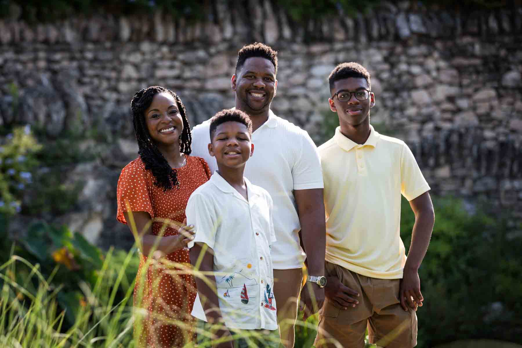 Japanese Tea Garden family portrait of an African American mother, father, and two sons standing in front of a stone wall