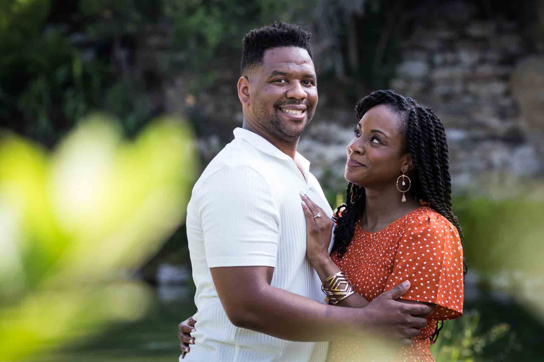 African American man and woman hugging in front of a pond during a Japanese Tea Garden engagement portrait