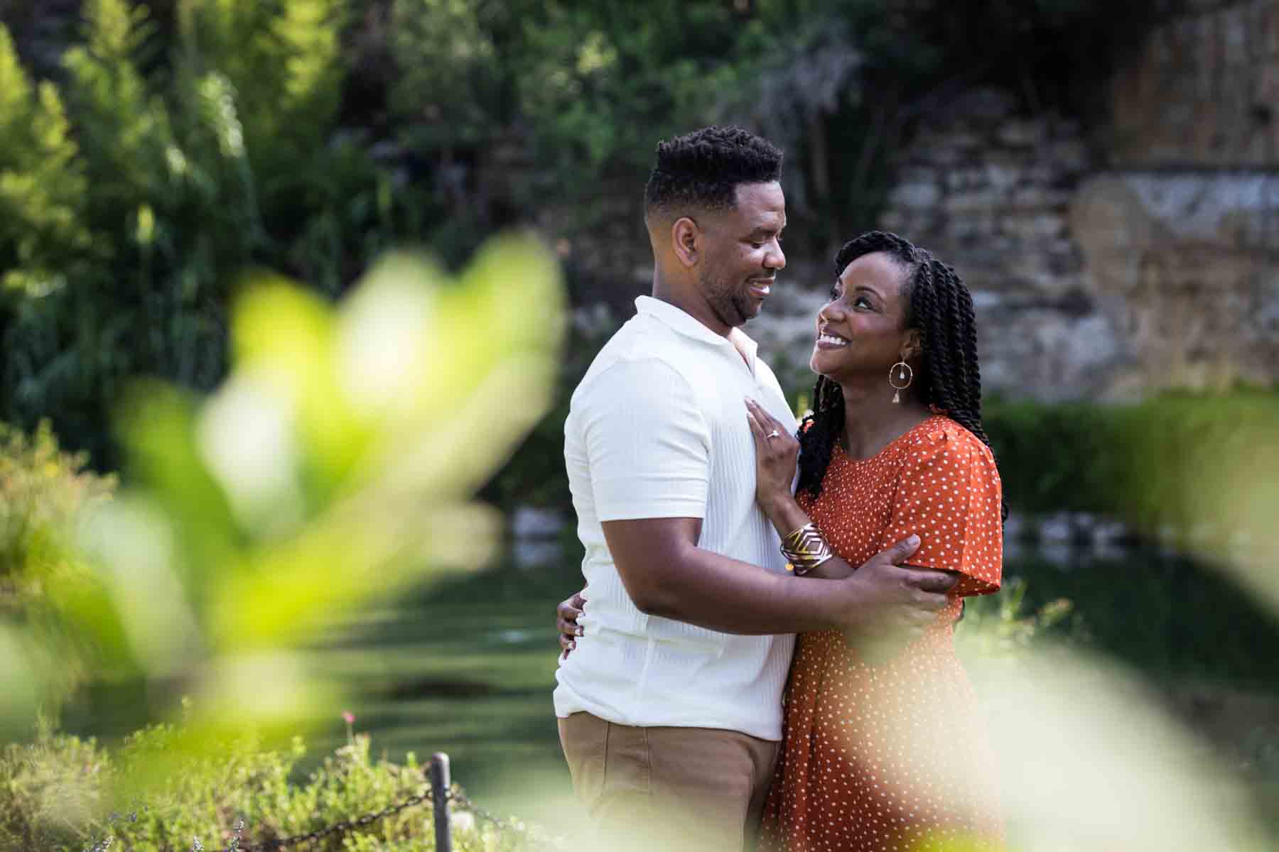 African American man and woman hugging in front of a pond during a Japanese Tea Garden engagement portrait