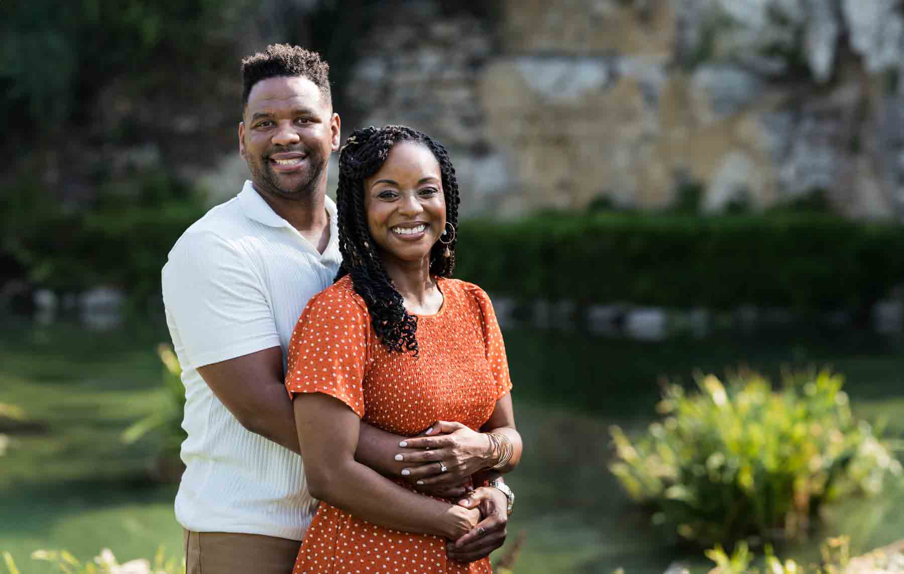 African American man and woman hugging in front of a pond during a Japanese Tea Garden engagement portrait