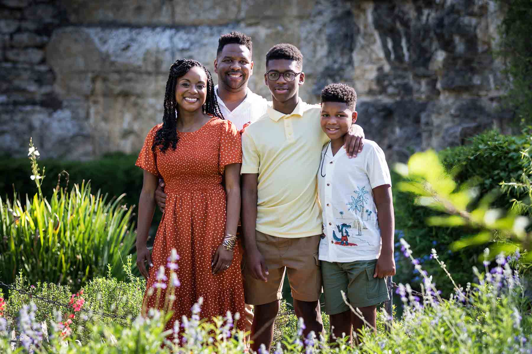 Japanese Tea Garden family portrait of an African American mother, father, and two sons standing in front of a stone wall