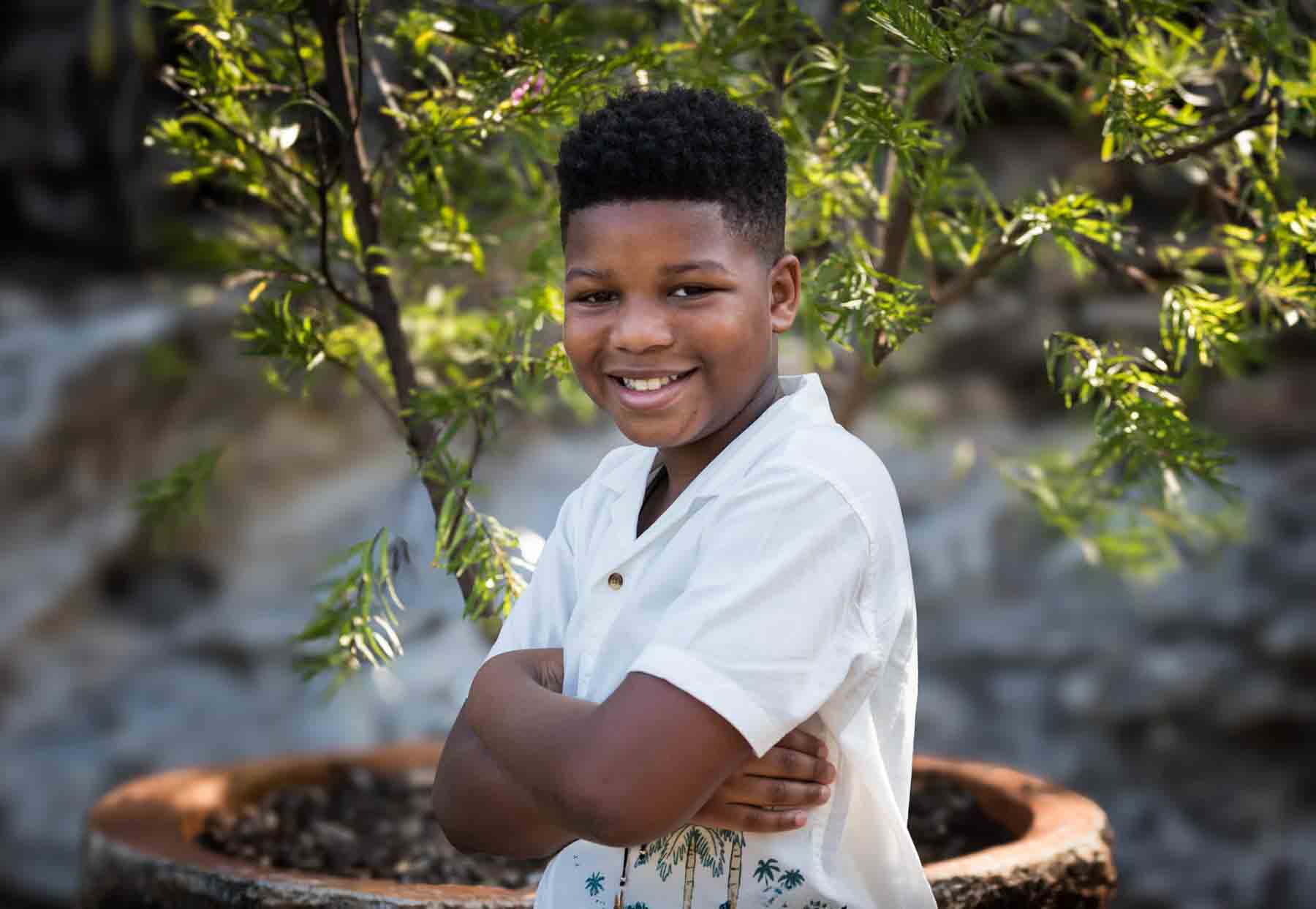 Young African American man wearing white shirt with arms crossed standing in front of plants in the Japanese Tea Garden