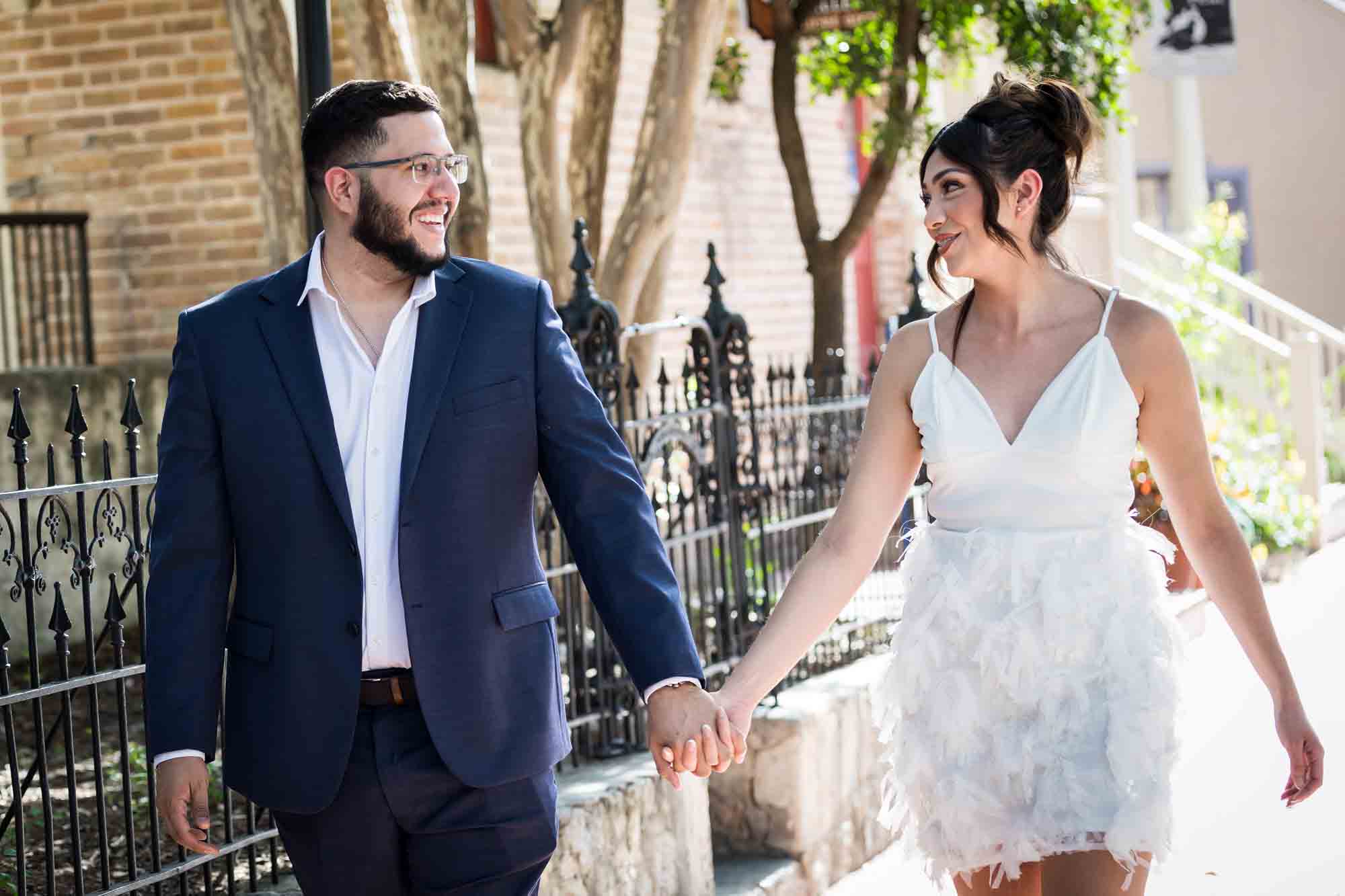 La Villita engagement photos of couple holding hands and walking on sidewalk