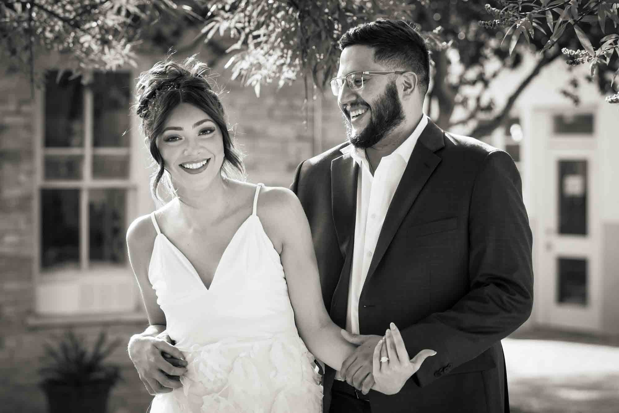 Black and white La Villita engagement photos of man looking at woman wearing white, sleeveless dress