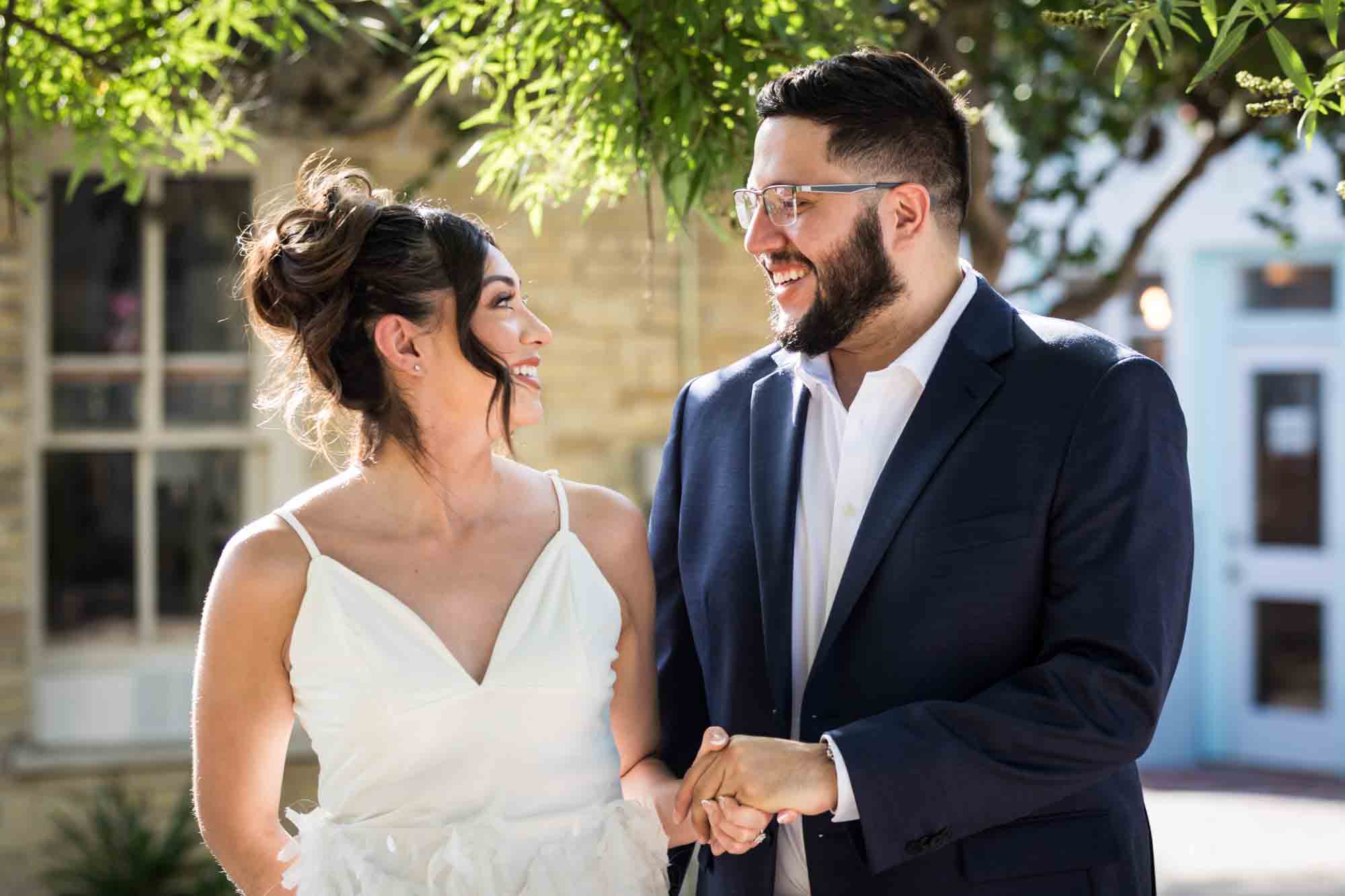 La Villita engagement photos of couple holding hands in patio with tree branch in background