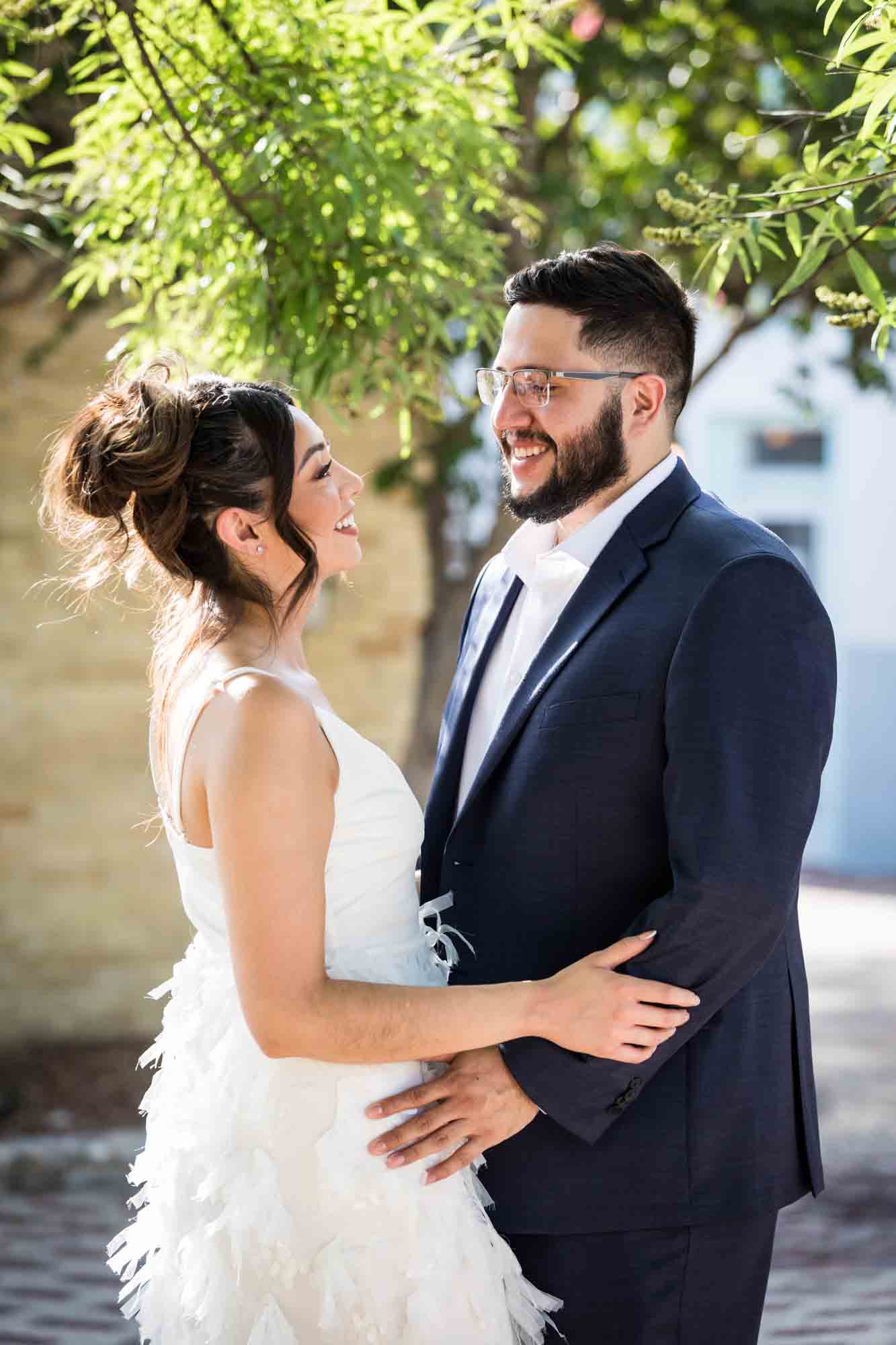 La Villita engagement photos of couple hugging in patio with tree branch in background