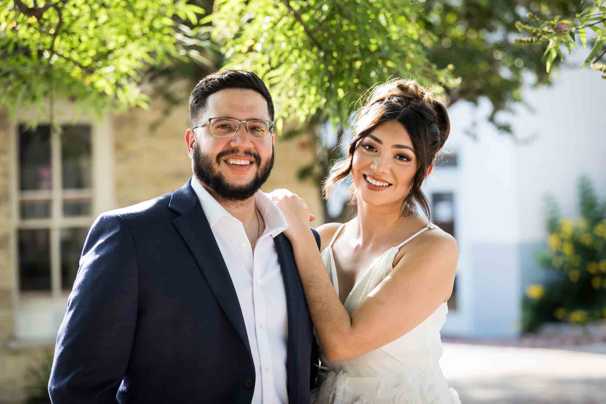 La Villita engagement photos of woman leaning on man's shoulder in patio with tree branch in background