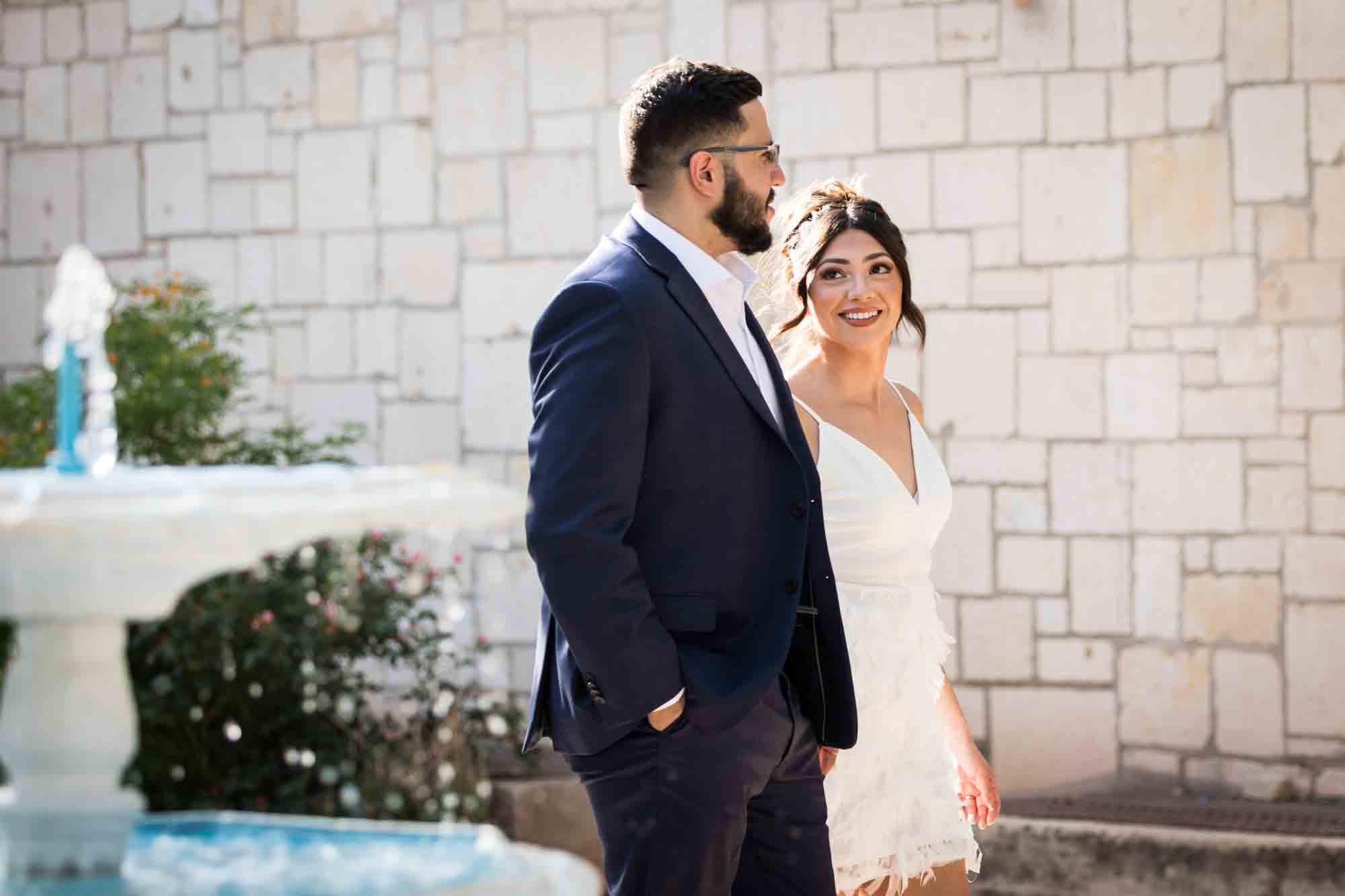 La Villita engagement photos of couple holding hands and walking around fountain