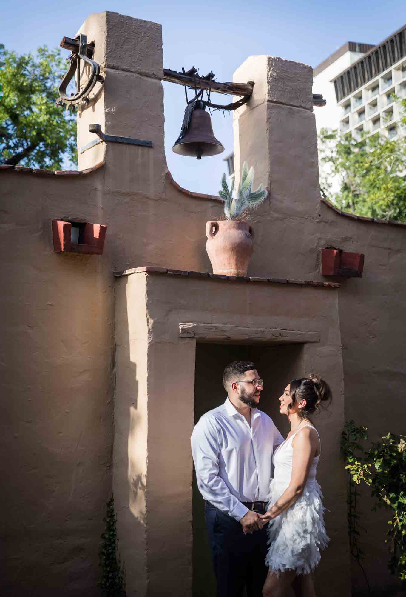 La Villita engagement photos of couple hugging in front of adobe building facade