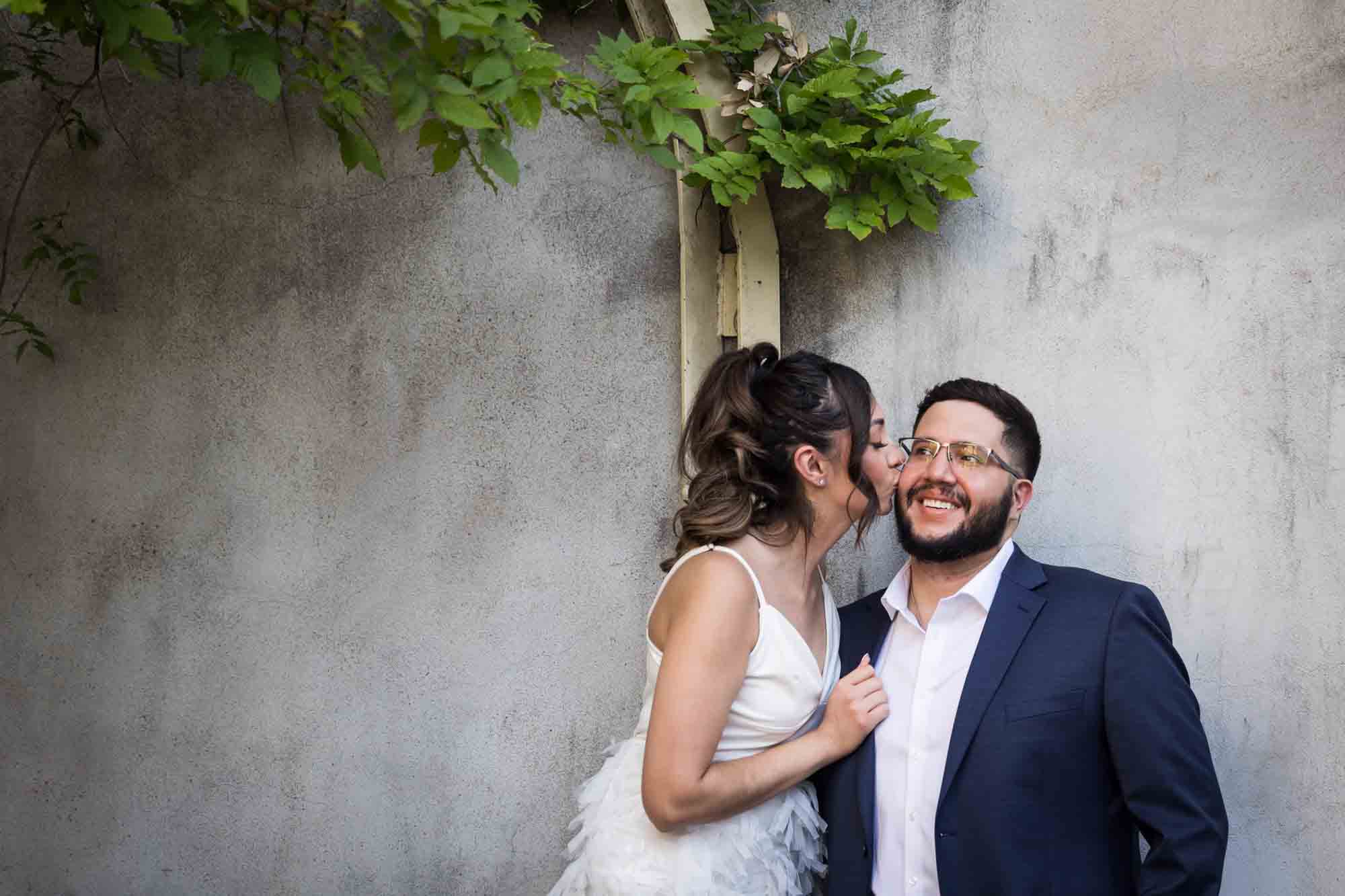 La Villita engagement photos of woman about to kiss man standing against wall with vines overhead