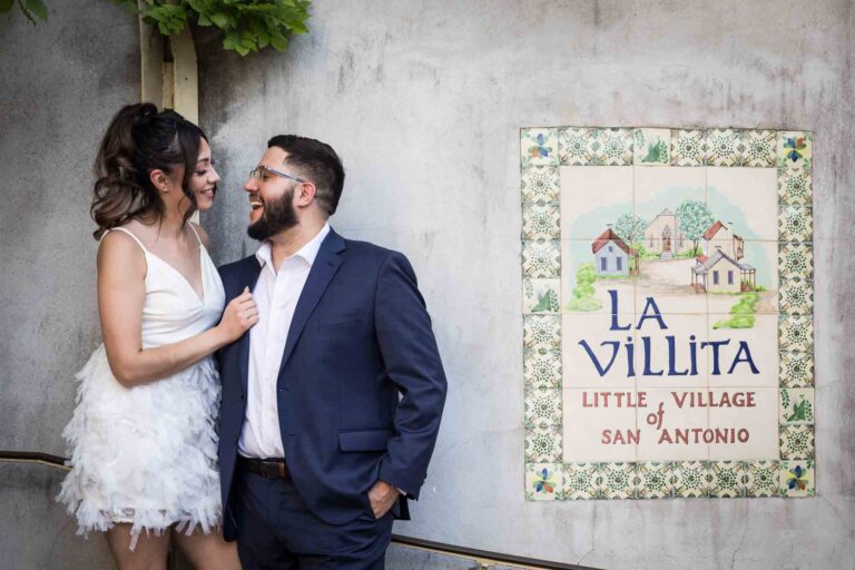 La Villita engagement photos of woman looking at man standing against wall with vines overhead