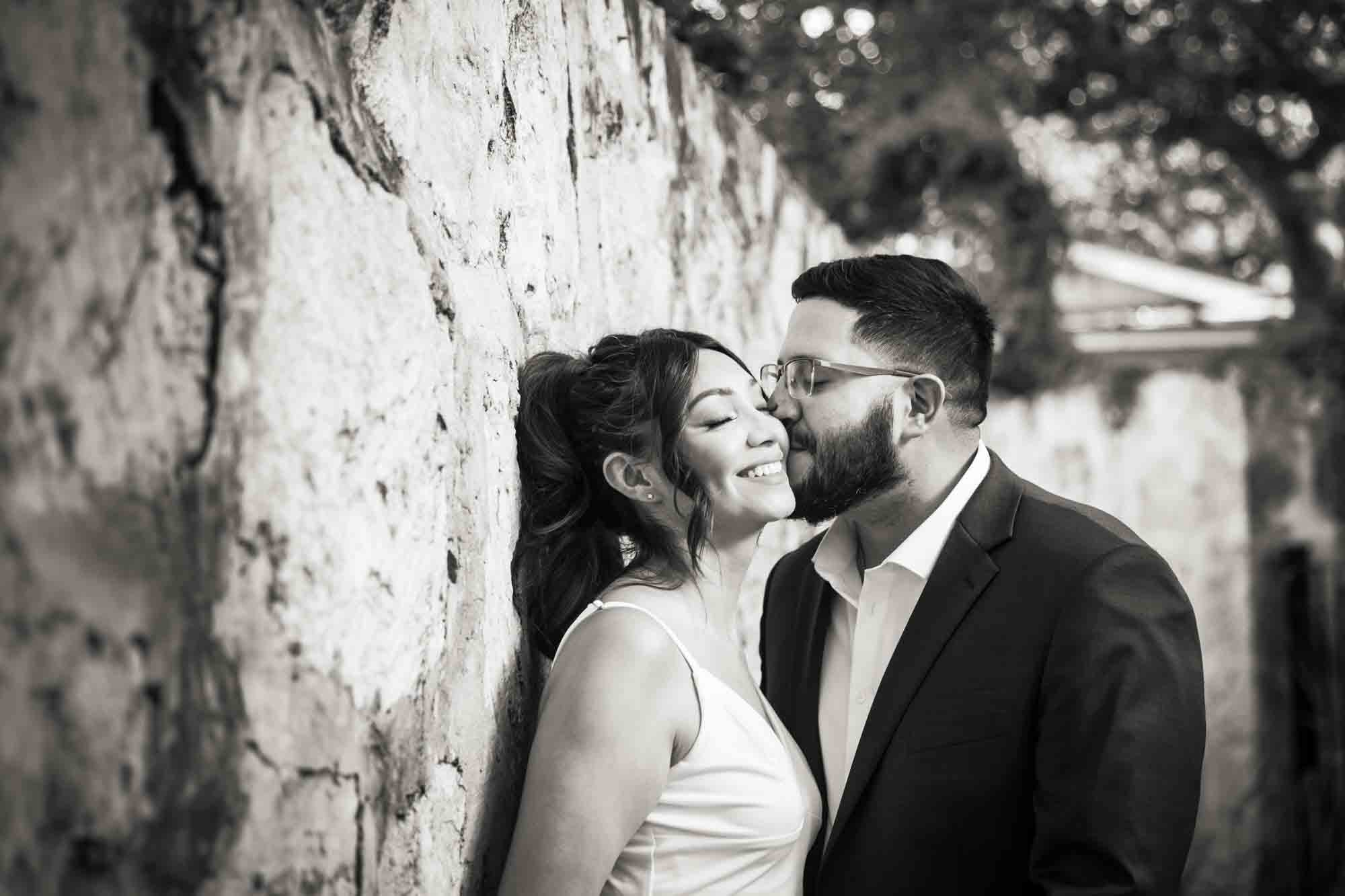 Black and white La Villita engagement photos of man kissing woman on the cheek