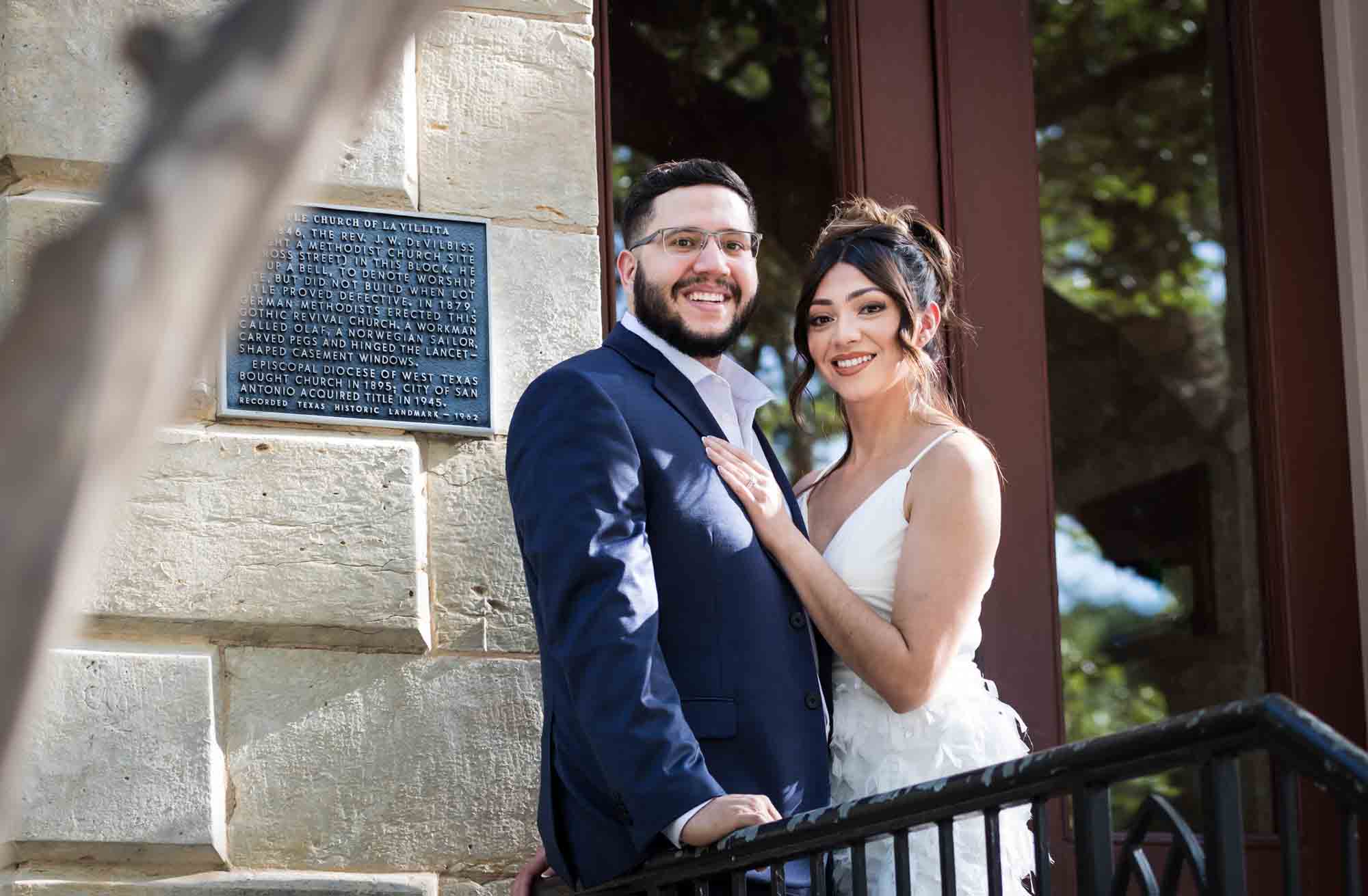 La Villita engagement photos of couple hugging against stair railing