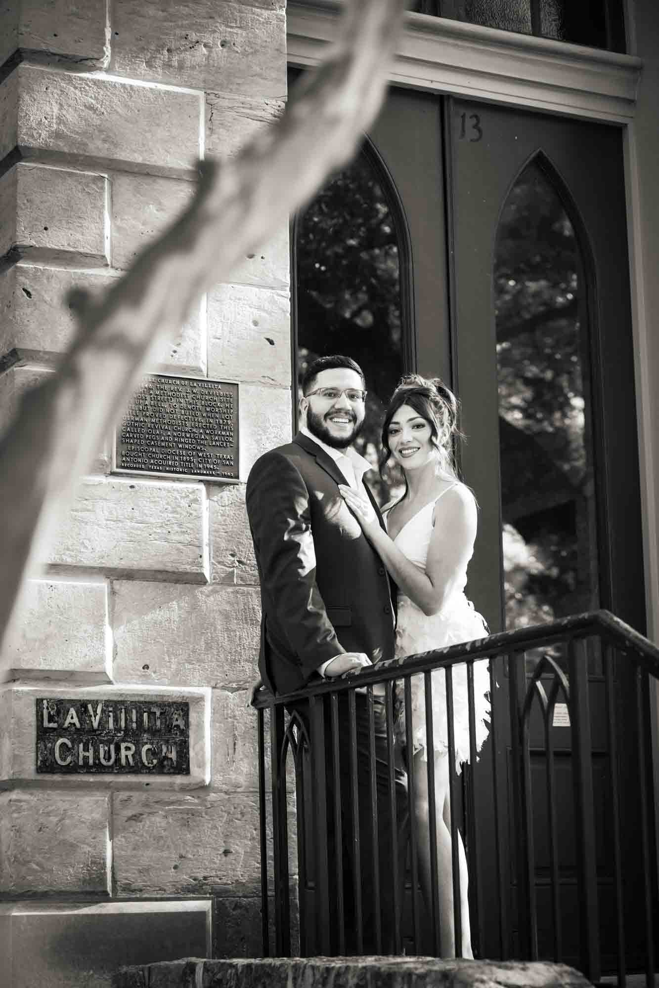 Black and white La Villita engagement photos of couple hugging against stair railing