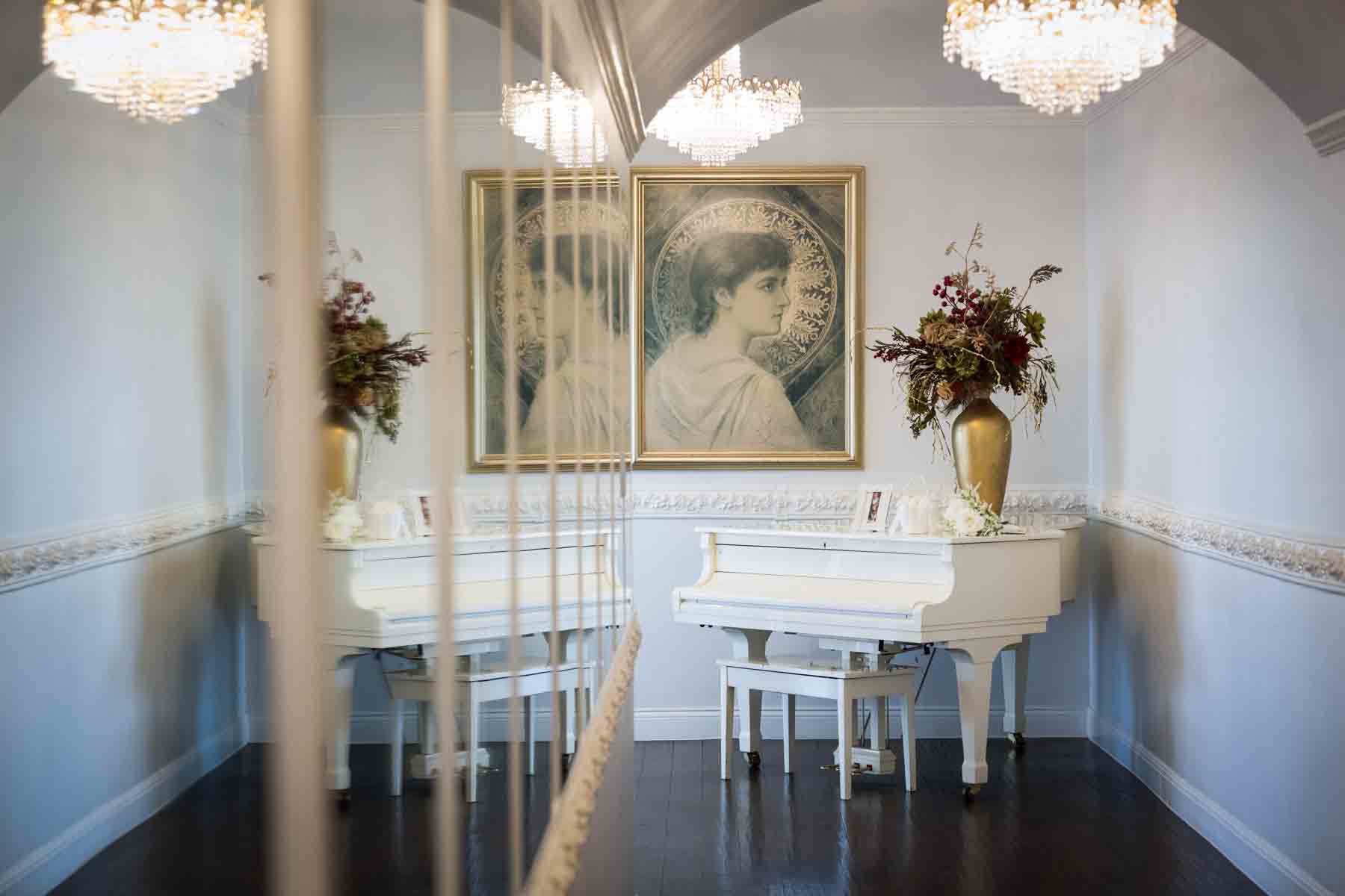 White piano and gold vase with flowers in hallway reflected in mirror at an Old San Francisco Steakhouse wedding