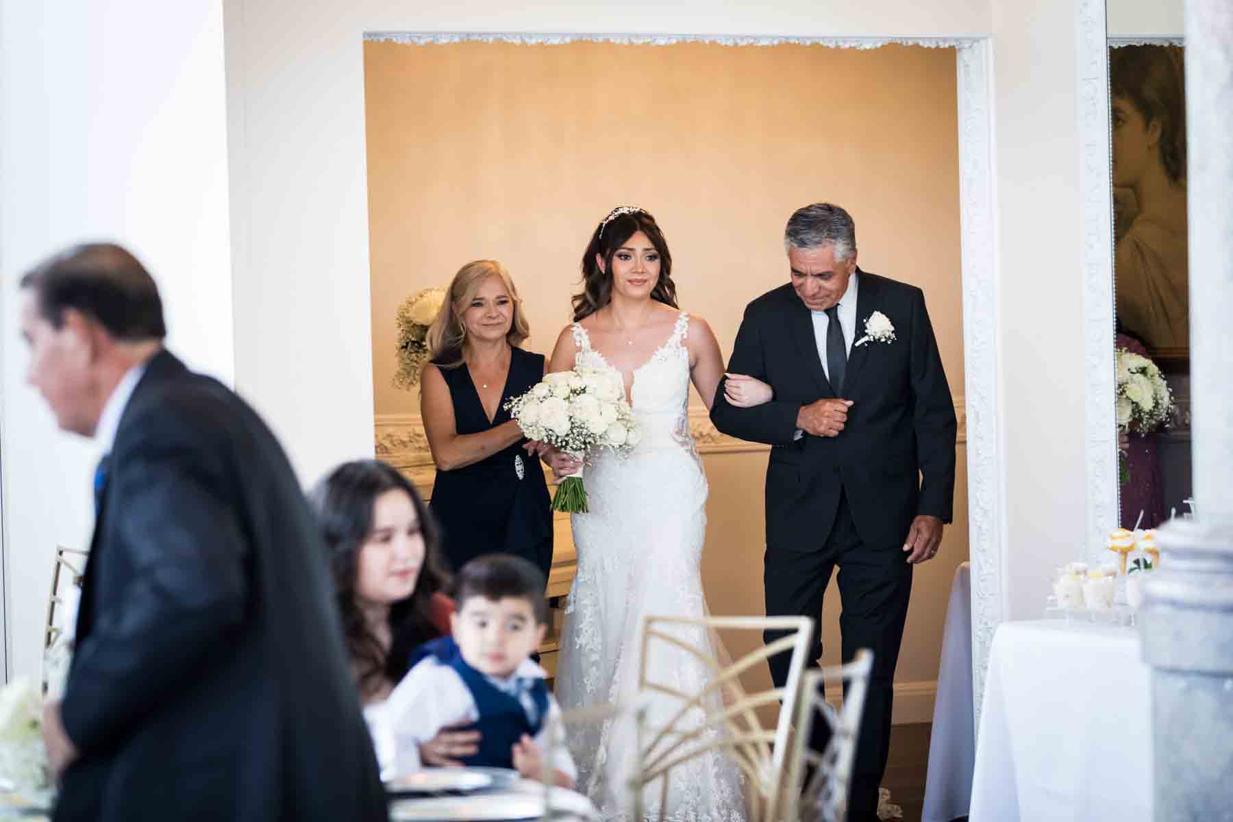 Bride escorted by her parents entering room during ceremony at an Old San Francisco Steakhouse wedding