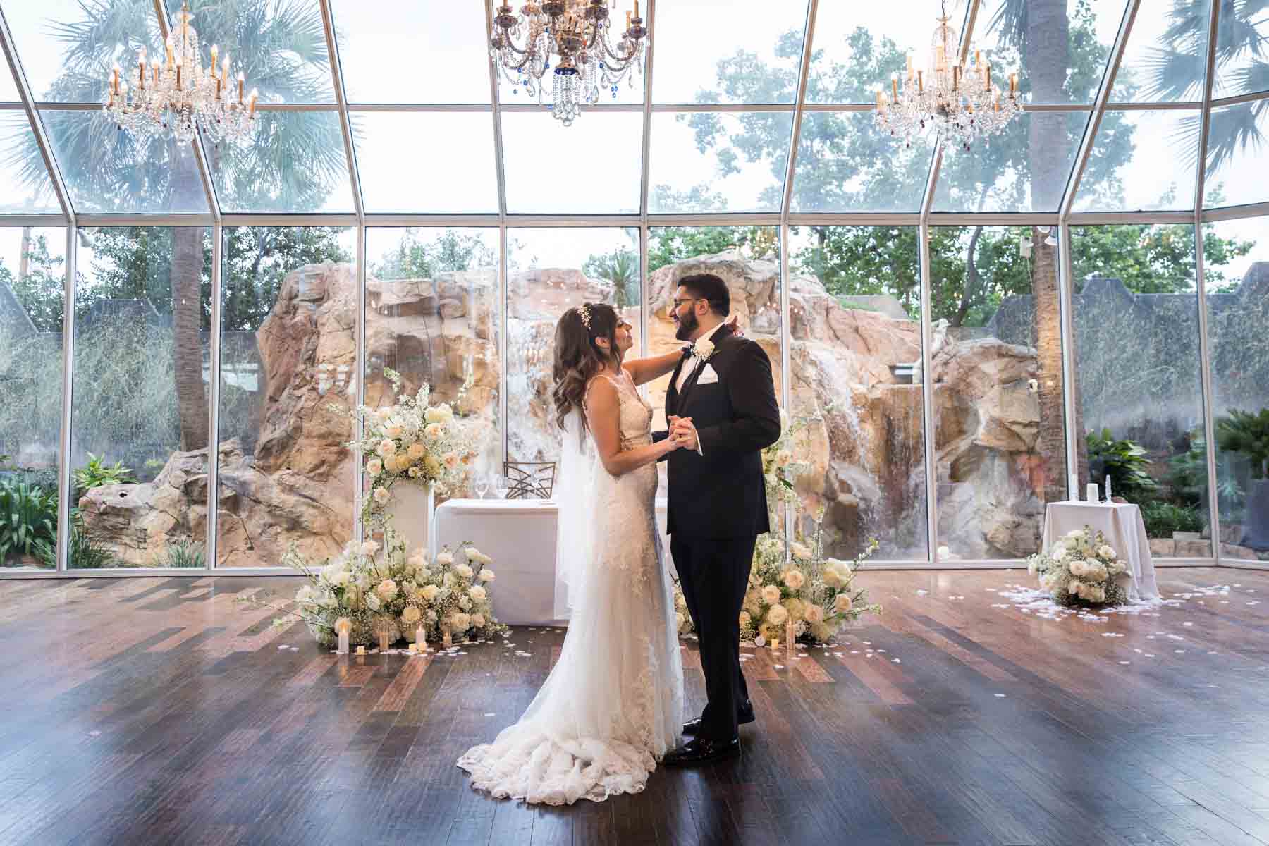 Old San Francisco wedding photos of bride and groom dancing in front of white table and glass wall