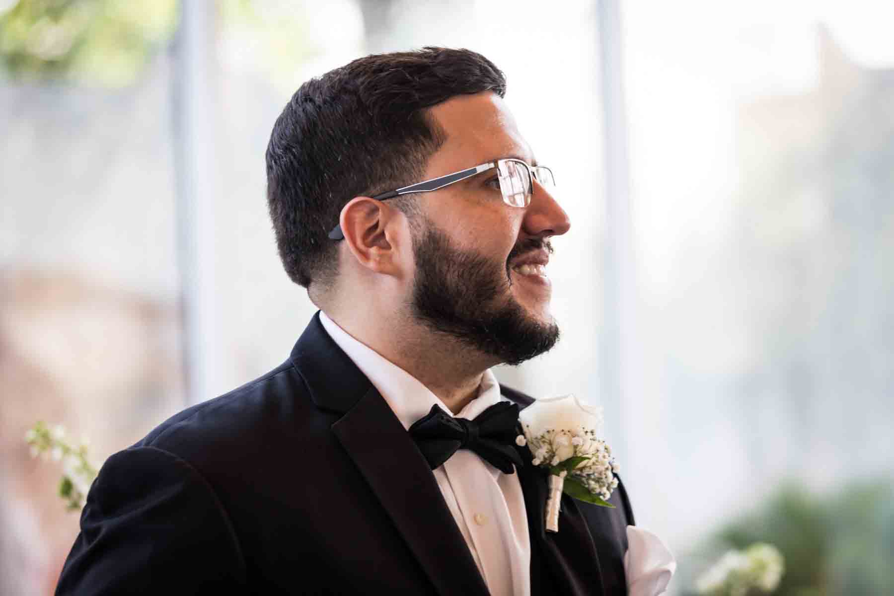 Groom wearing glasses, beard, and black tuxedo looking to right at an Old San Francisco Steakhouse wedding