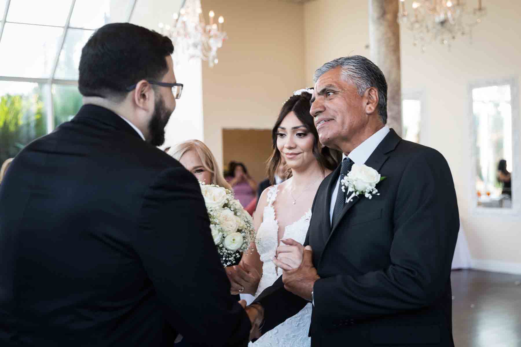 Bride's father shaking hand of groom in front of bride during ceremony at an Old San Francisco Steakhouse wedding