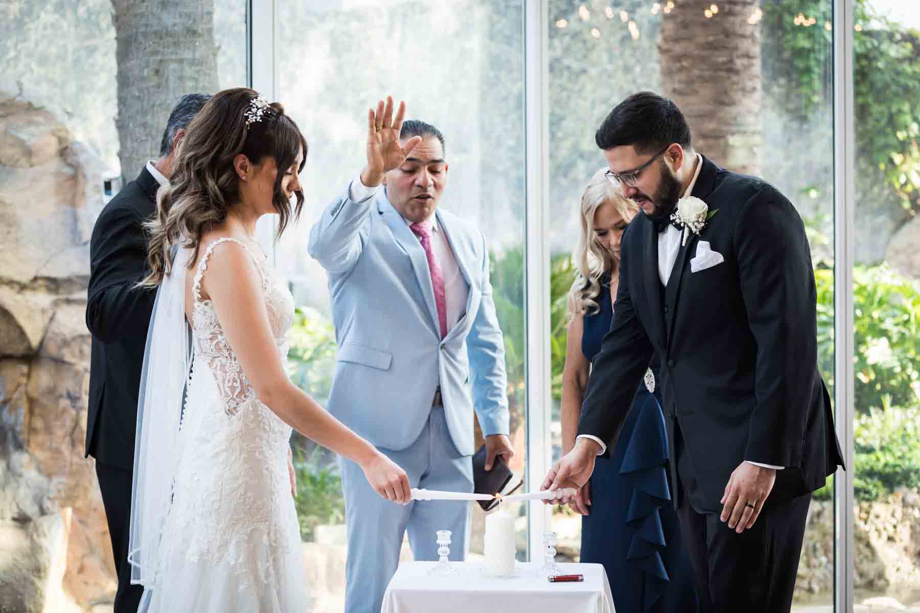 Old San Francisco wedding photos of bride and groom lighting unity candle together with officiant raising hand in background